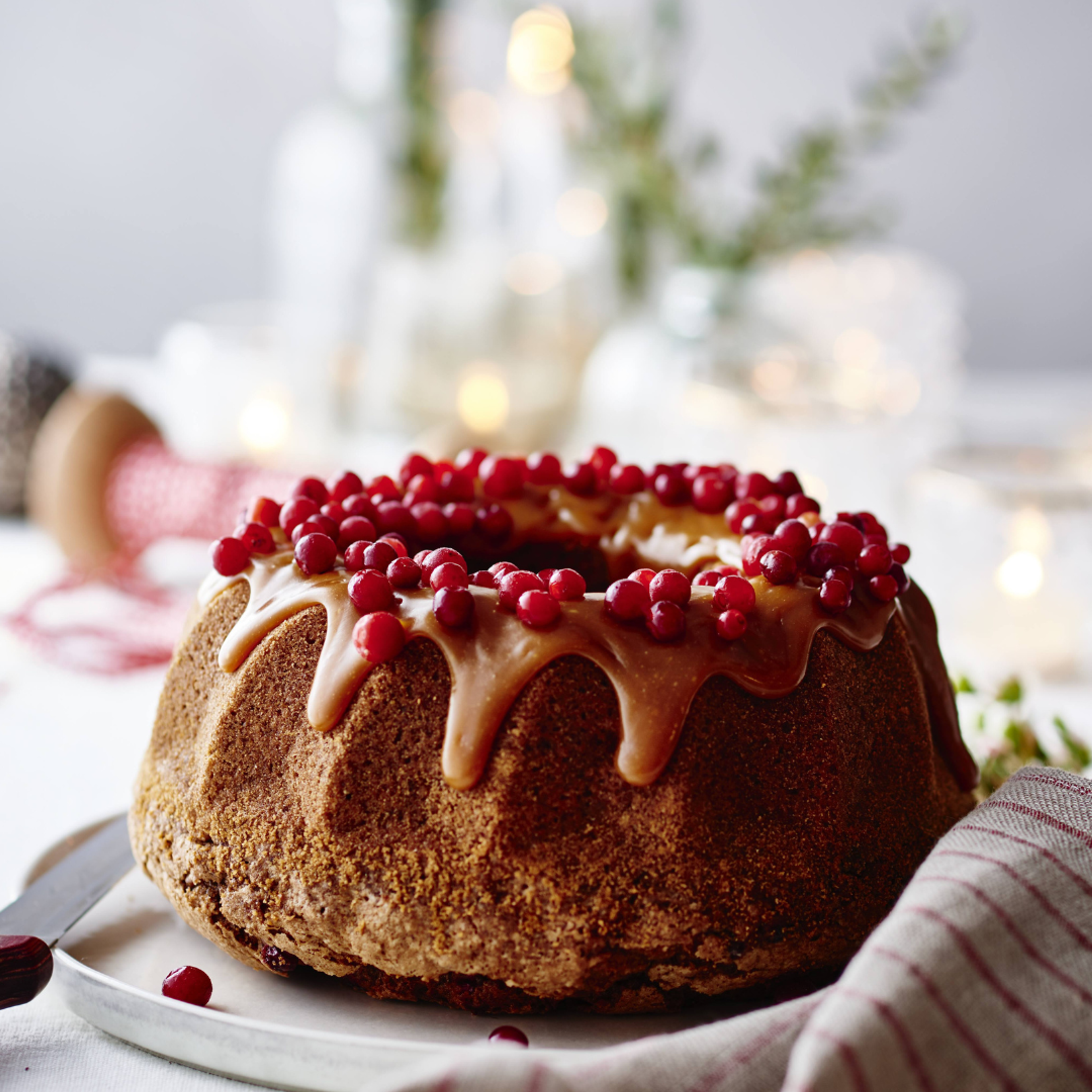 Mjuk pepparkaka toppad med kolasås och lingon, serverad på ett fat i julig miljö med ljus i bakgrunden.