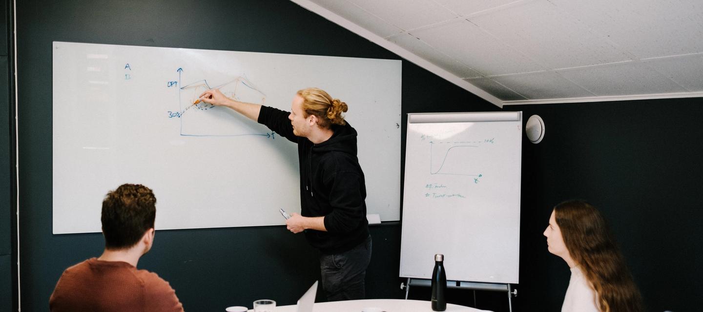 A Deepinsight employee shows something on a whiteboard in front of two colleagues.
