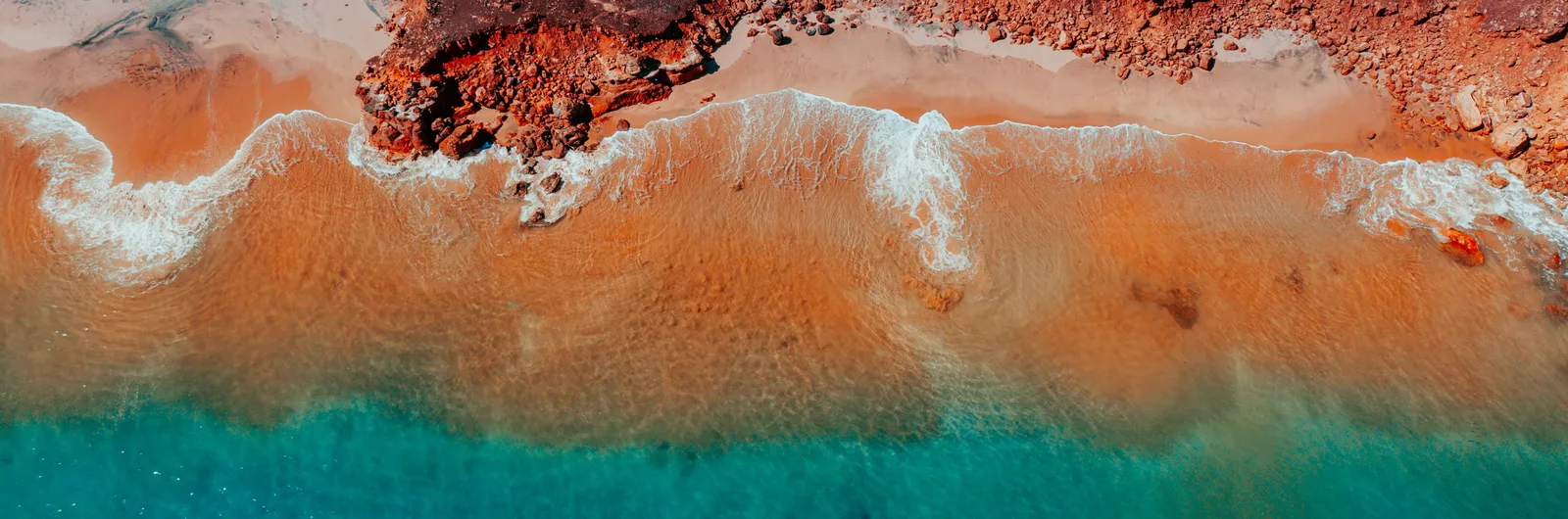 overhead view of water hitting rocks with vibrant colours