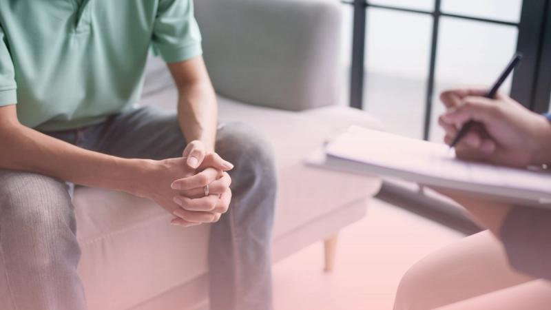 Paciente sentado en el sillón conversando con un terapeuta que toma notas, durante una sesión privada con nuestros psicólogos especialistas.
