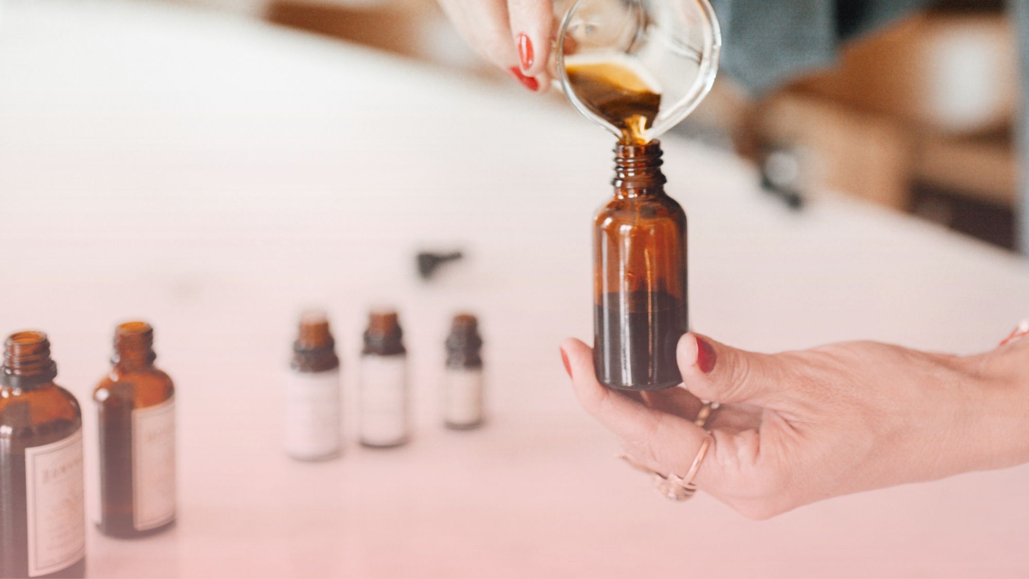 Manos preparando un remedio natural en gotas desde un frasco ámbar, representando los tratamientos de nuestro médico homeópata y flores de bach.