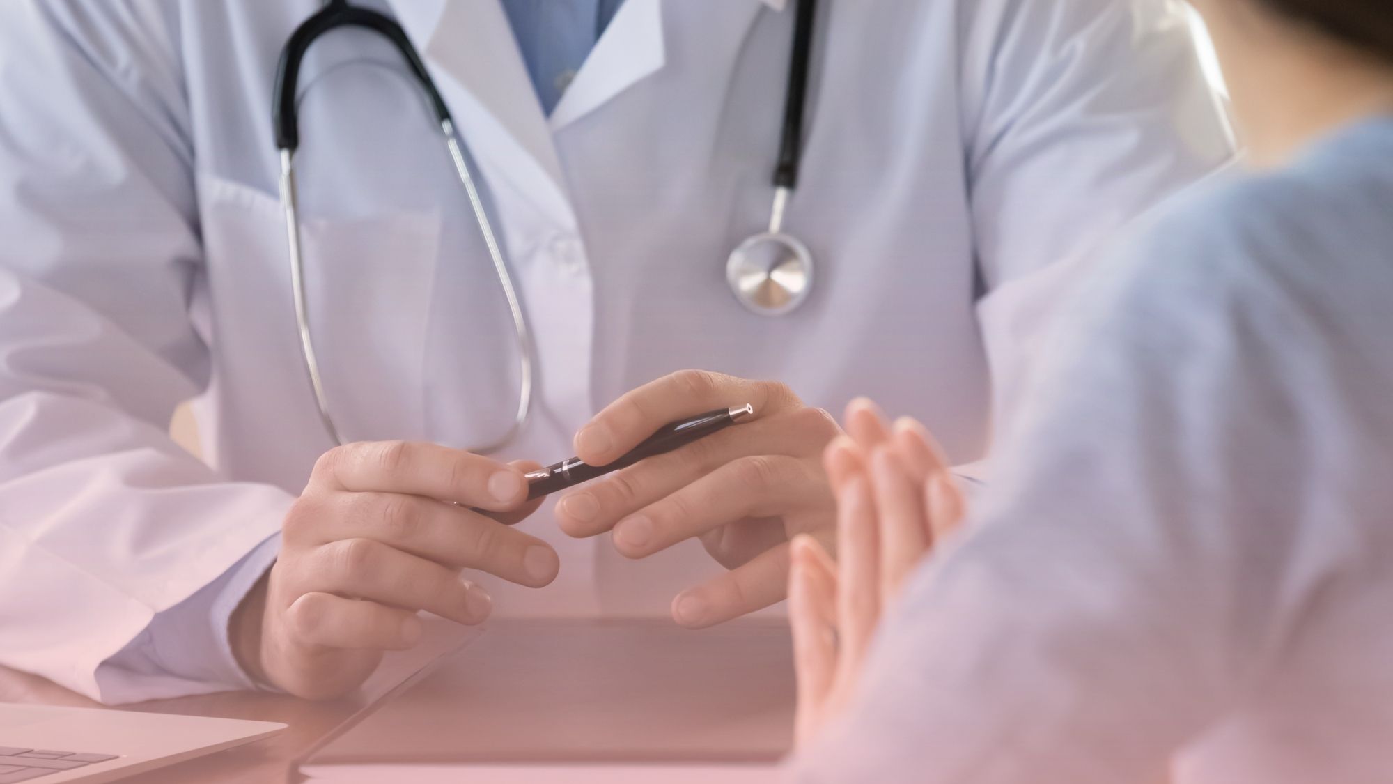 Médico clínico conversando amablemente con un paciente durante una consulta de rutina en el escritorio, ideal para su chequeo médico anual preventivo.
