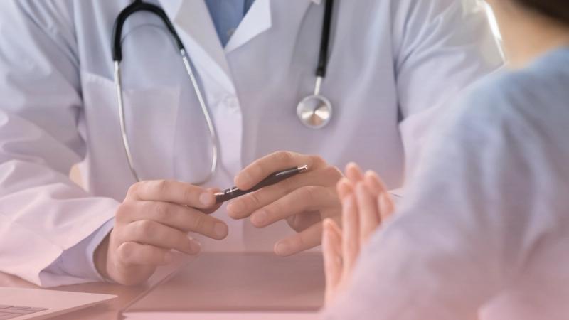 Médico clínico conversando amablemente con un paciente durante una consulta de rutina en el escritorio, ideal para su chequeo médico anual preventivo.