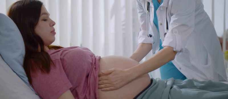 Licenciada en obstetricia sosteniendo la panza de una embarazada en una consulta reflejando la privacidad y empatía de nuestro servicio de obstetricia.