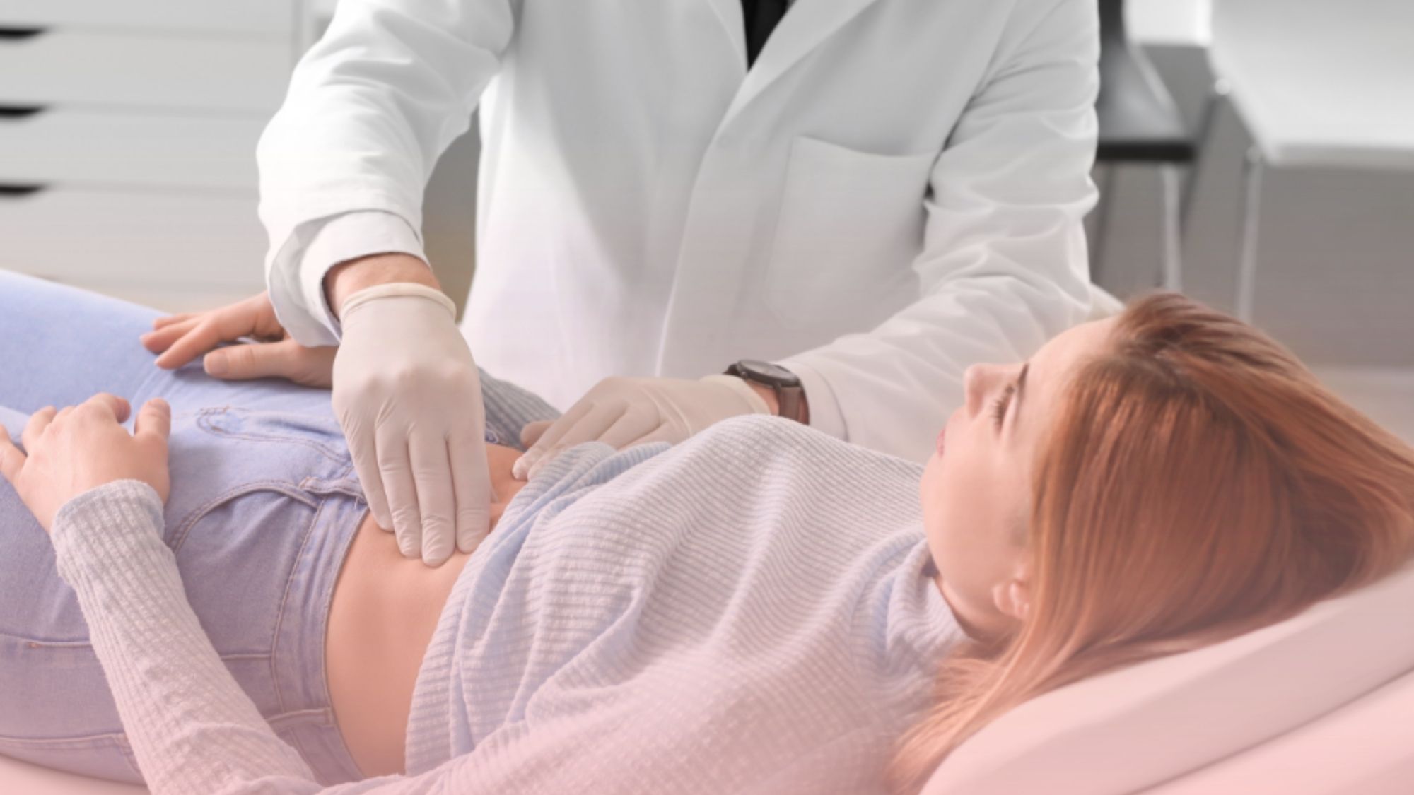 Médico gastroenterólogo realizando un examen abdominal manual a una paciente recostada en camilla para el diagnóstico de afecciones digestivas.