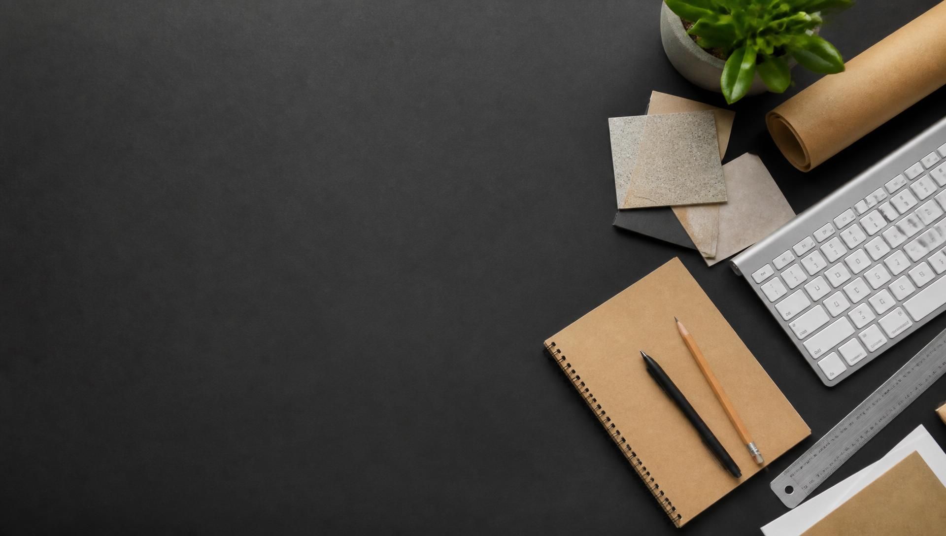 Secretária de design vista de cima com teclado, caderno kraft, régua e amostras de materiais