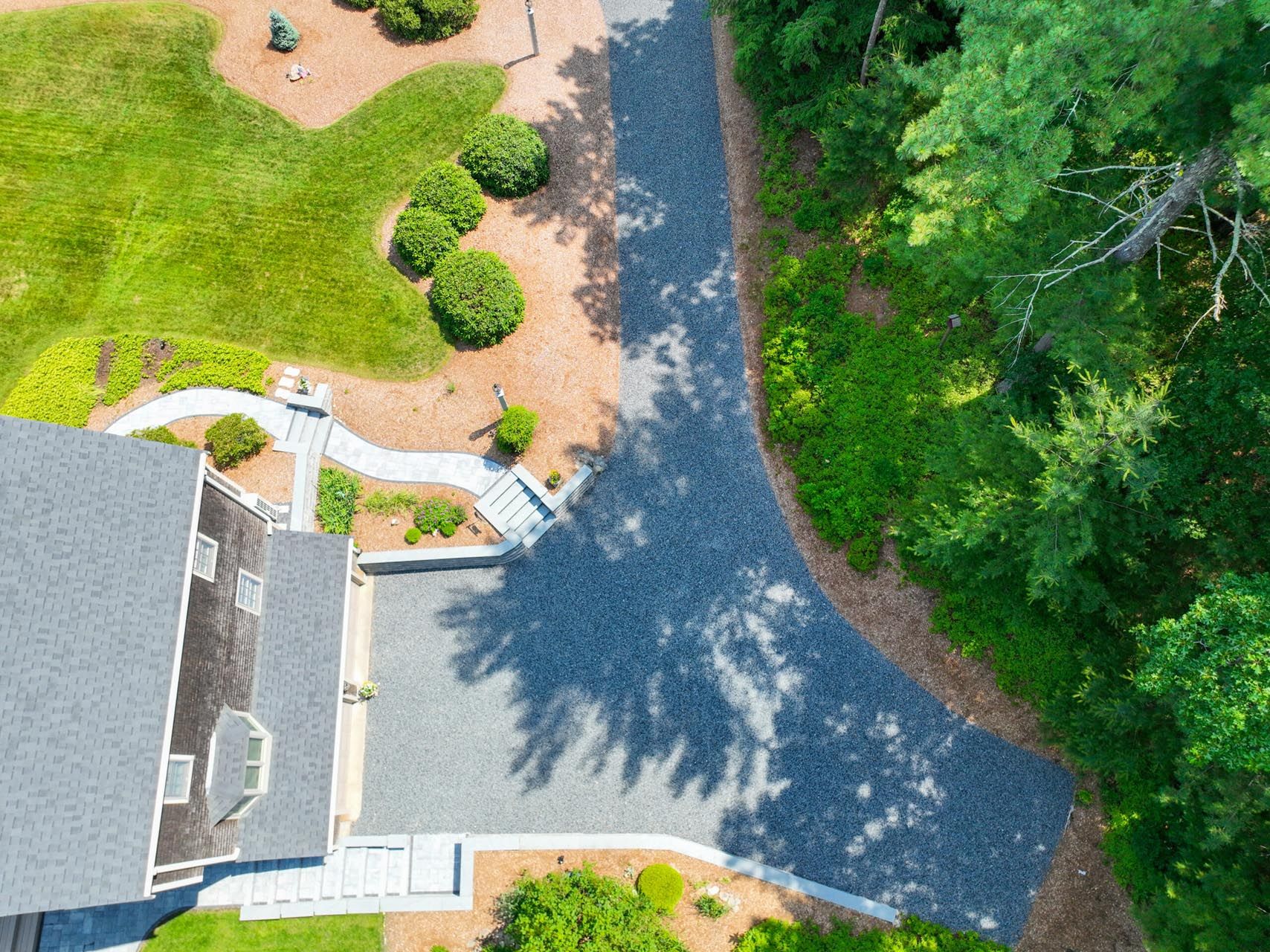 Aerial view of a completed residential hardscaping project featuring a paver driveway, walkway, stairs, and retaining wall by Contrast Landscape