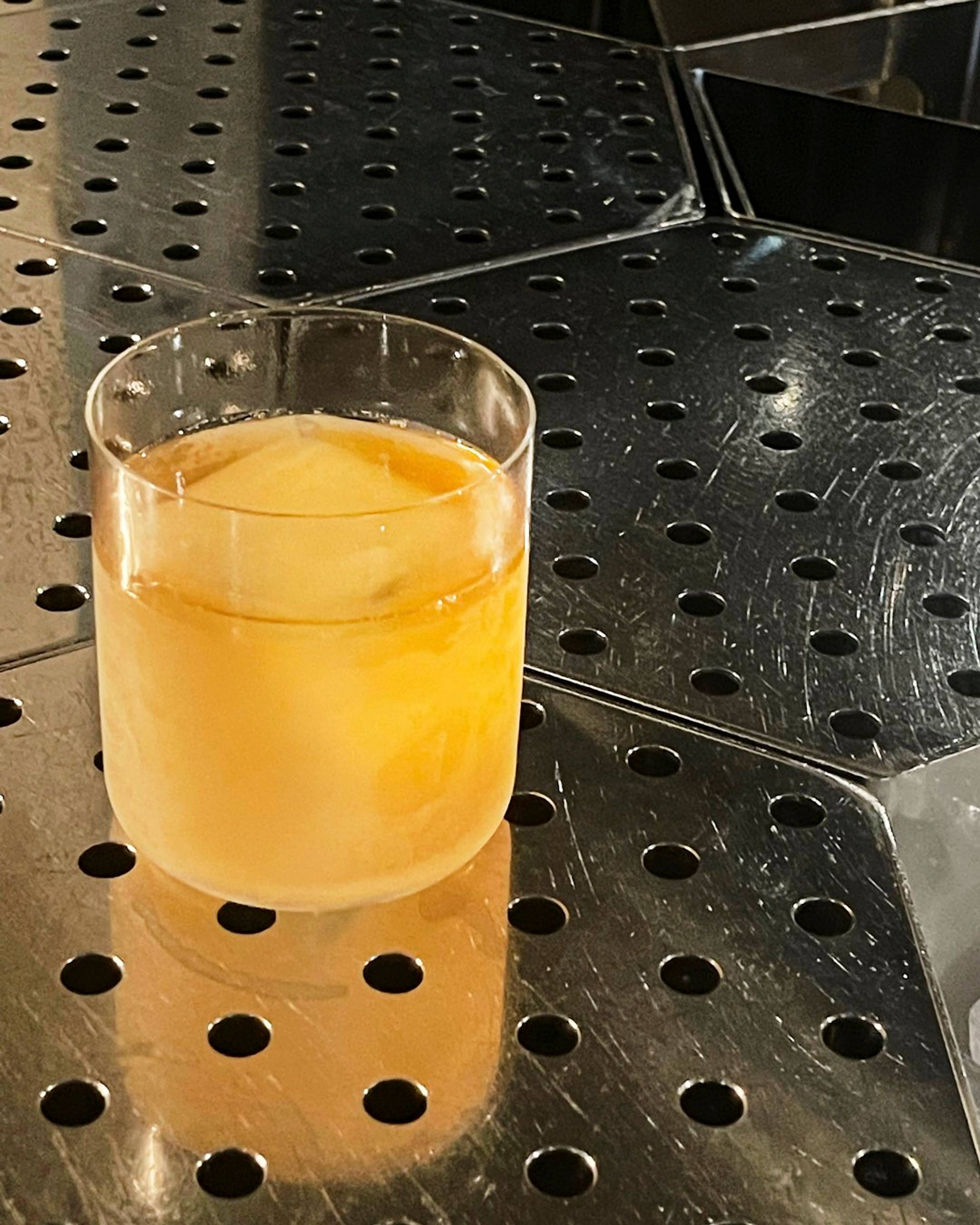 Mango cocktail served in a tumbler with a big cube of ice