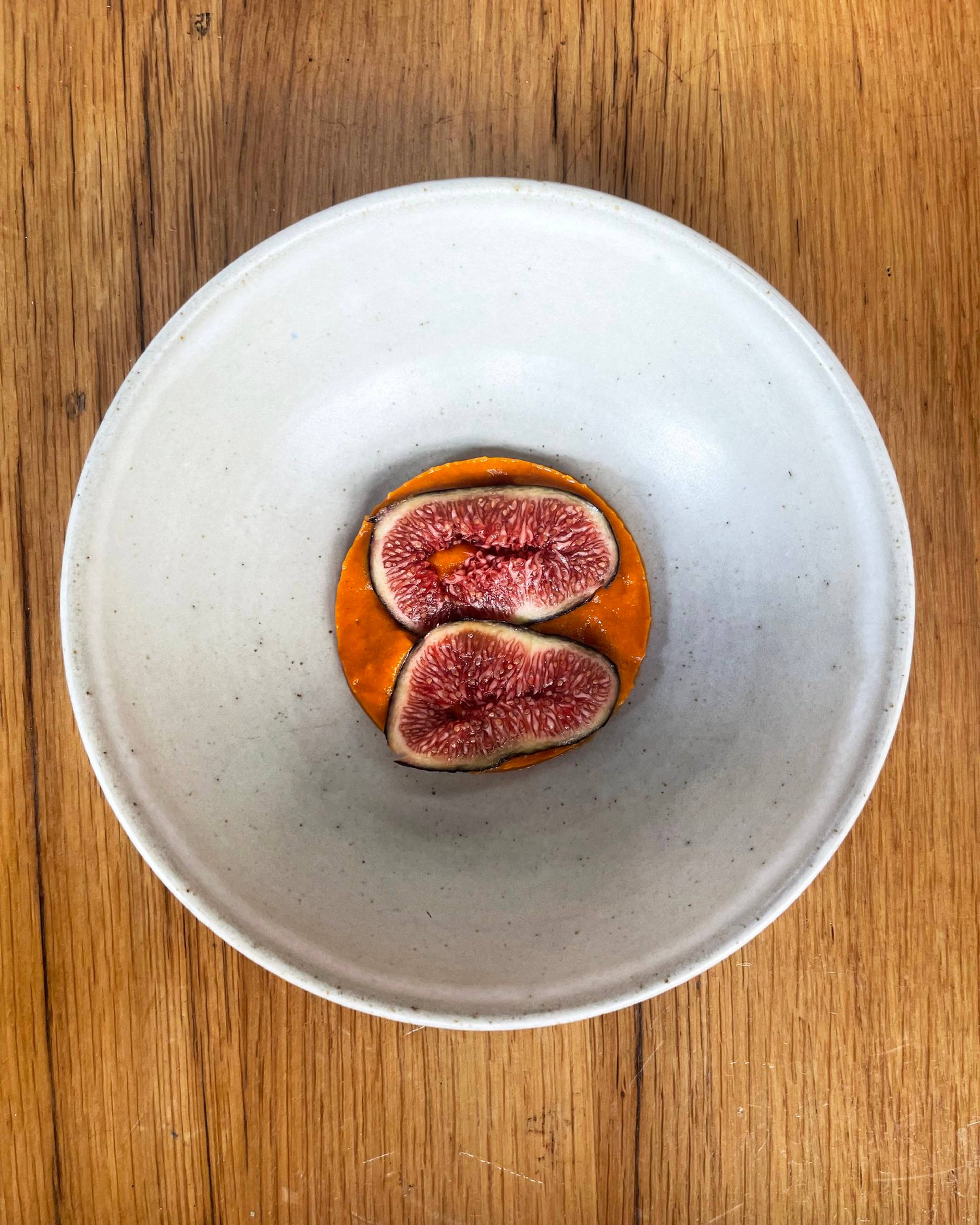 Black figs placed on top of the confit tomato sauce
