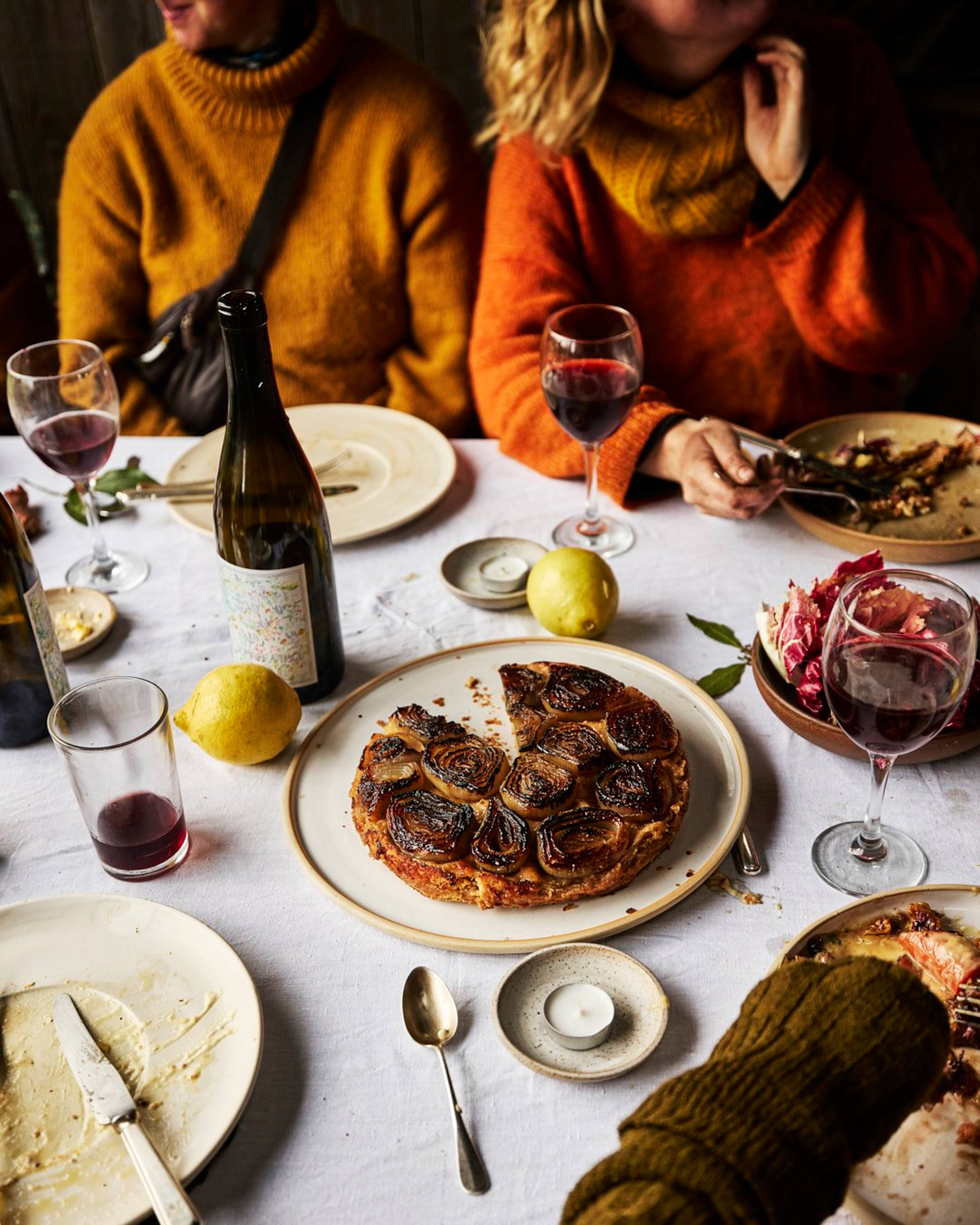 roscoff onion tart on a table with red wine and people eating