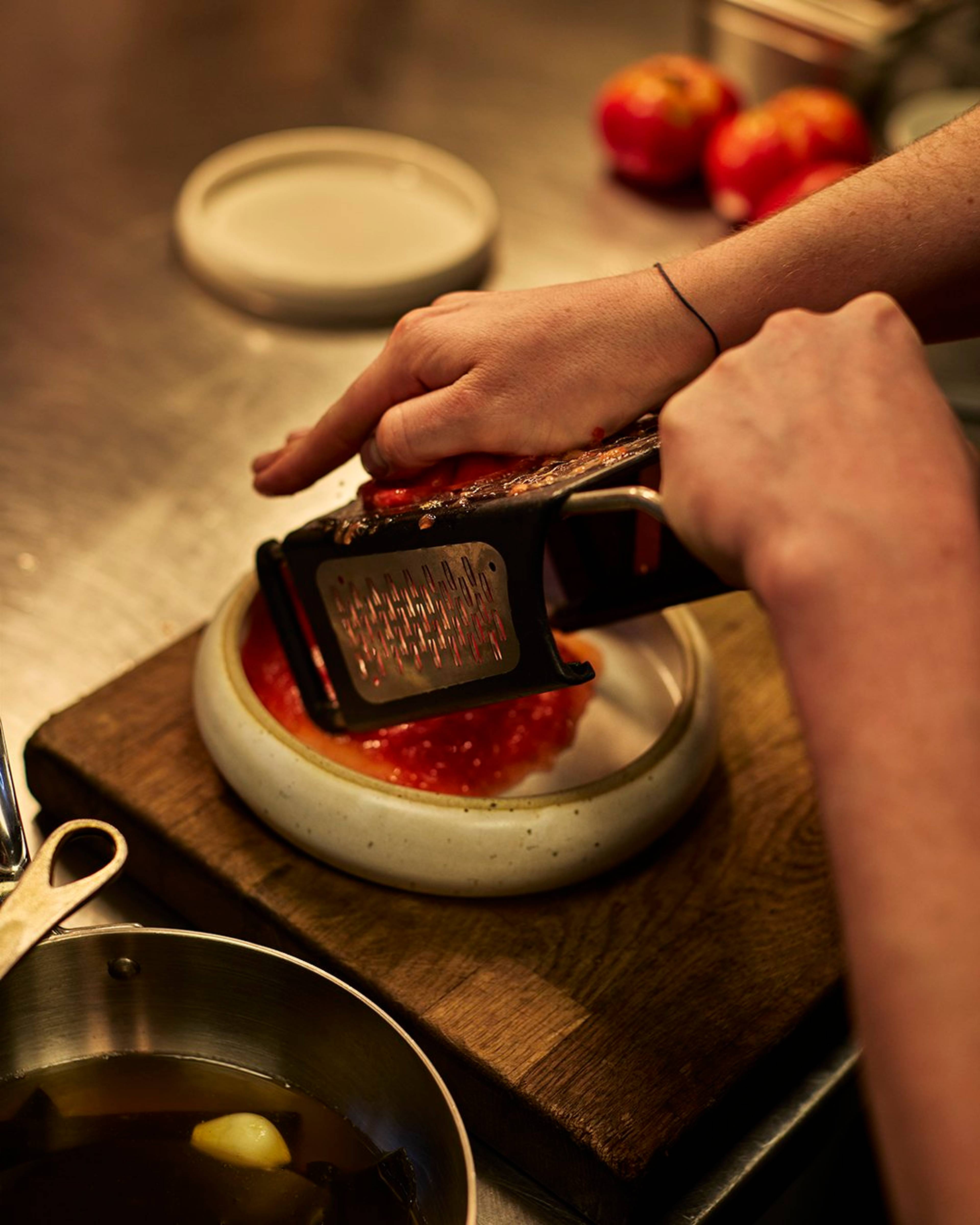tomato being grated into a bowl
