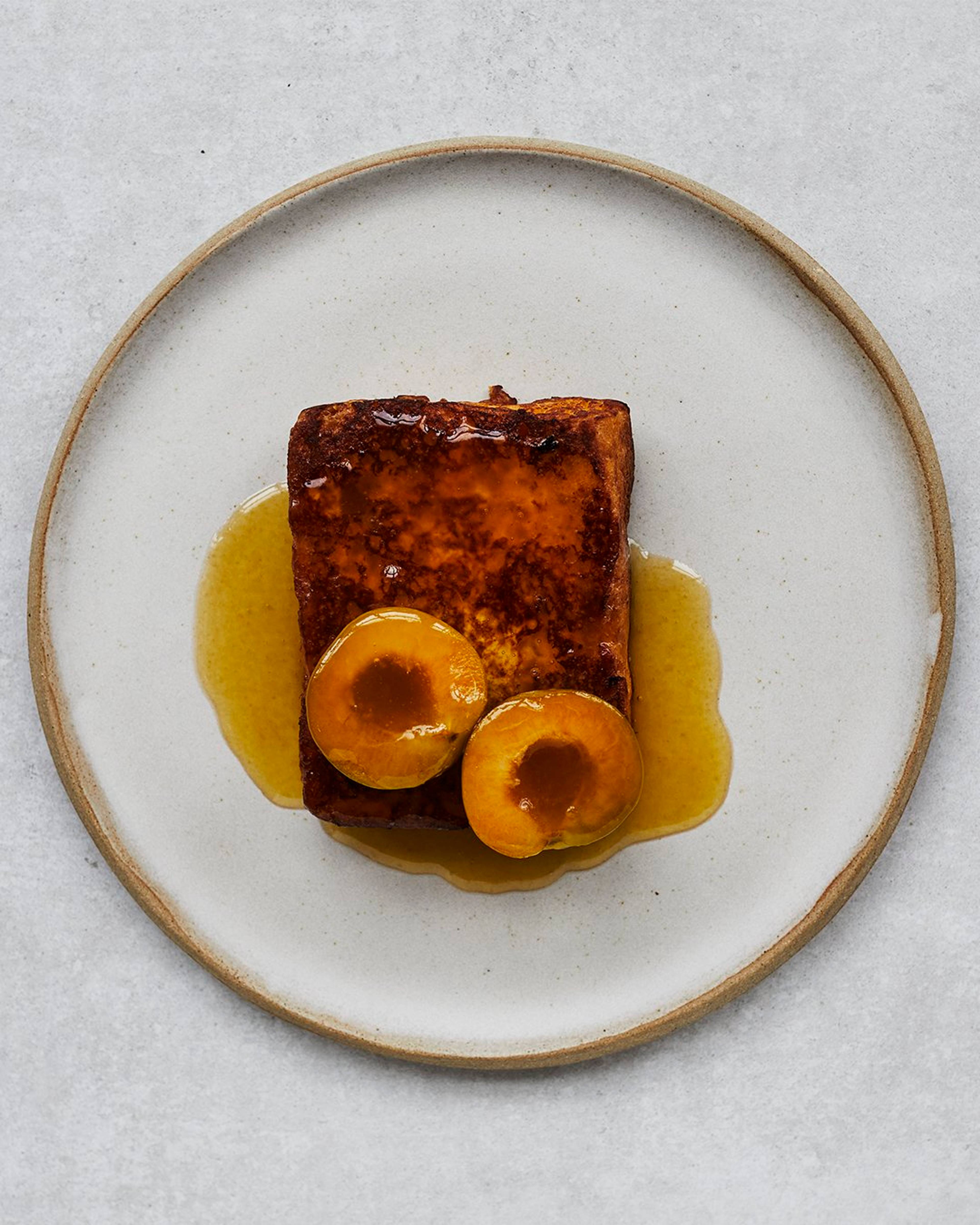 french toast served with plums and syrup on a plate