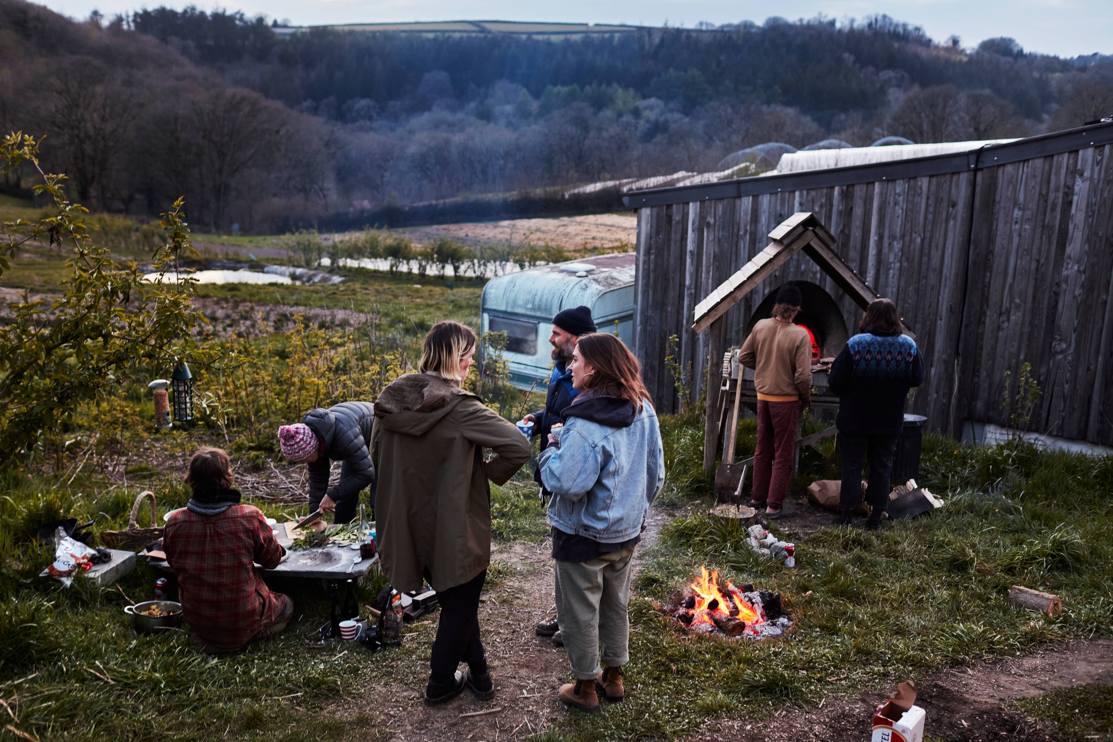 Group of people cooking and talking around the fire on a farm