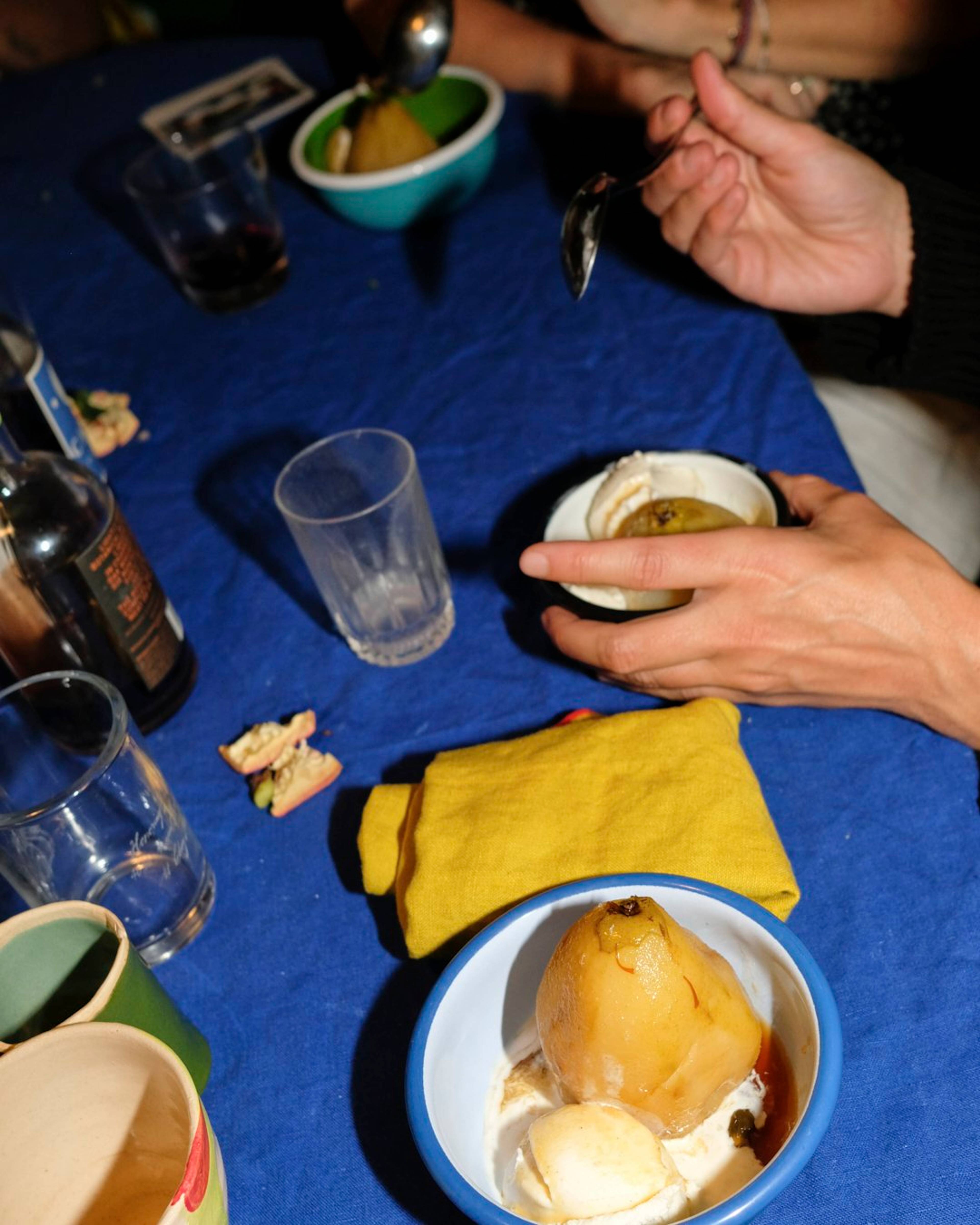 poached pears being eaten out bowls at the dinner table with yellow and blue table linens