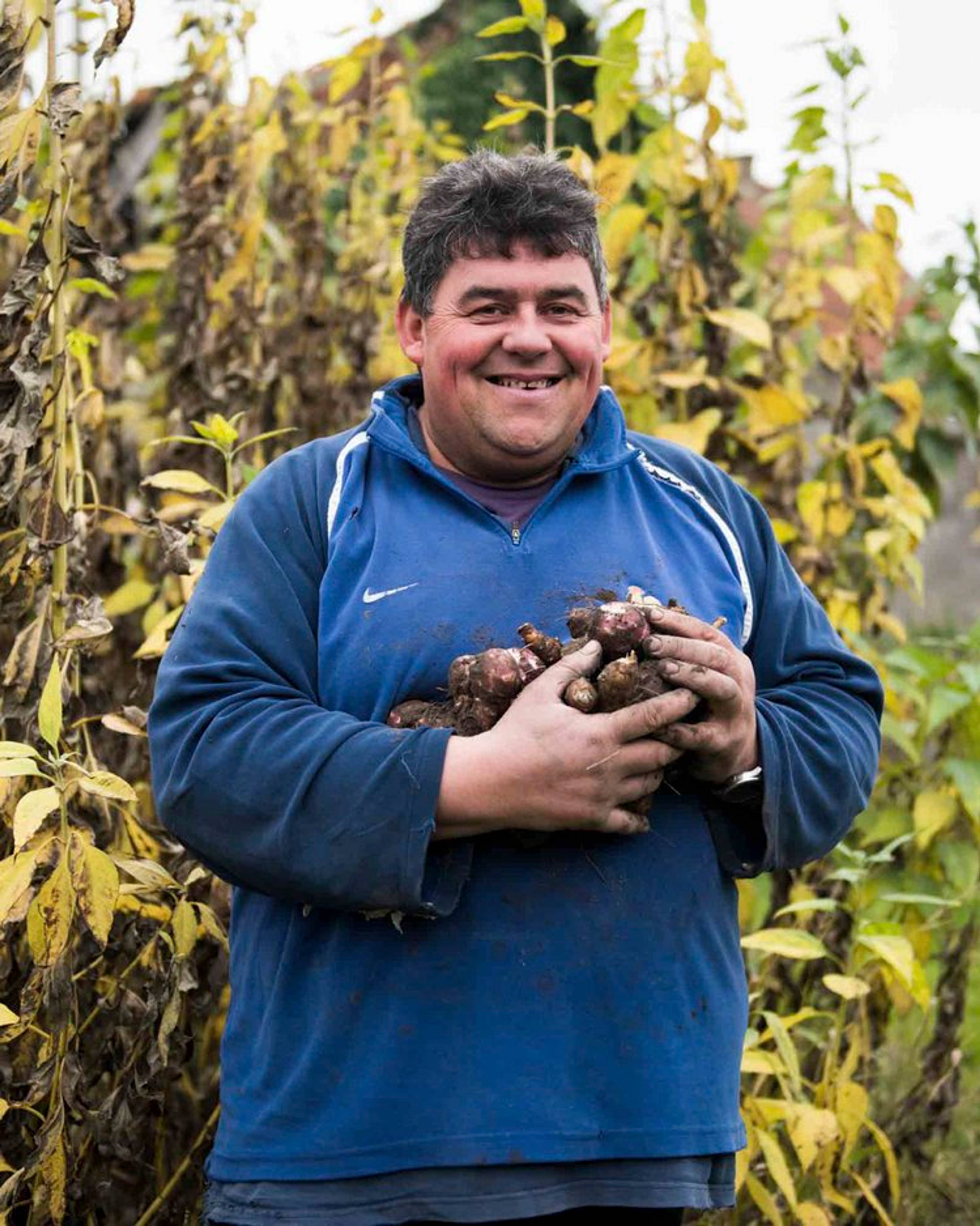 francois holding some jerusalem artichokes and smiling at the camera