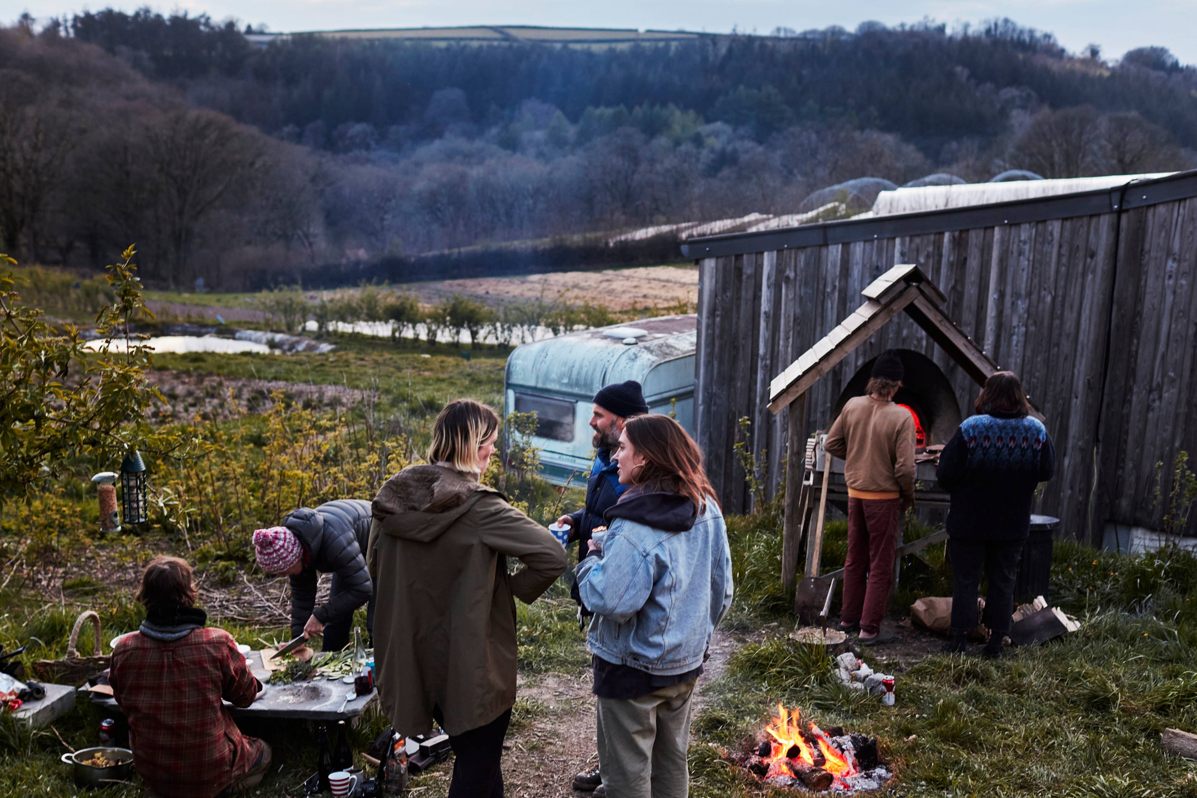 Group of people cooking and talking around the fire on a farm