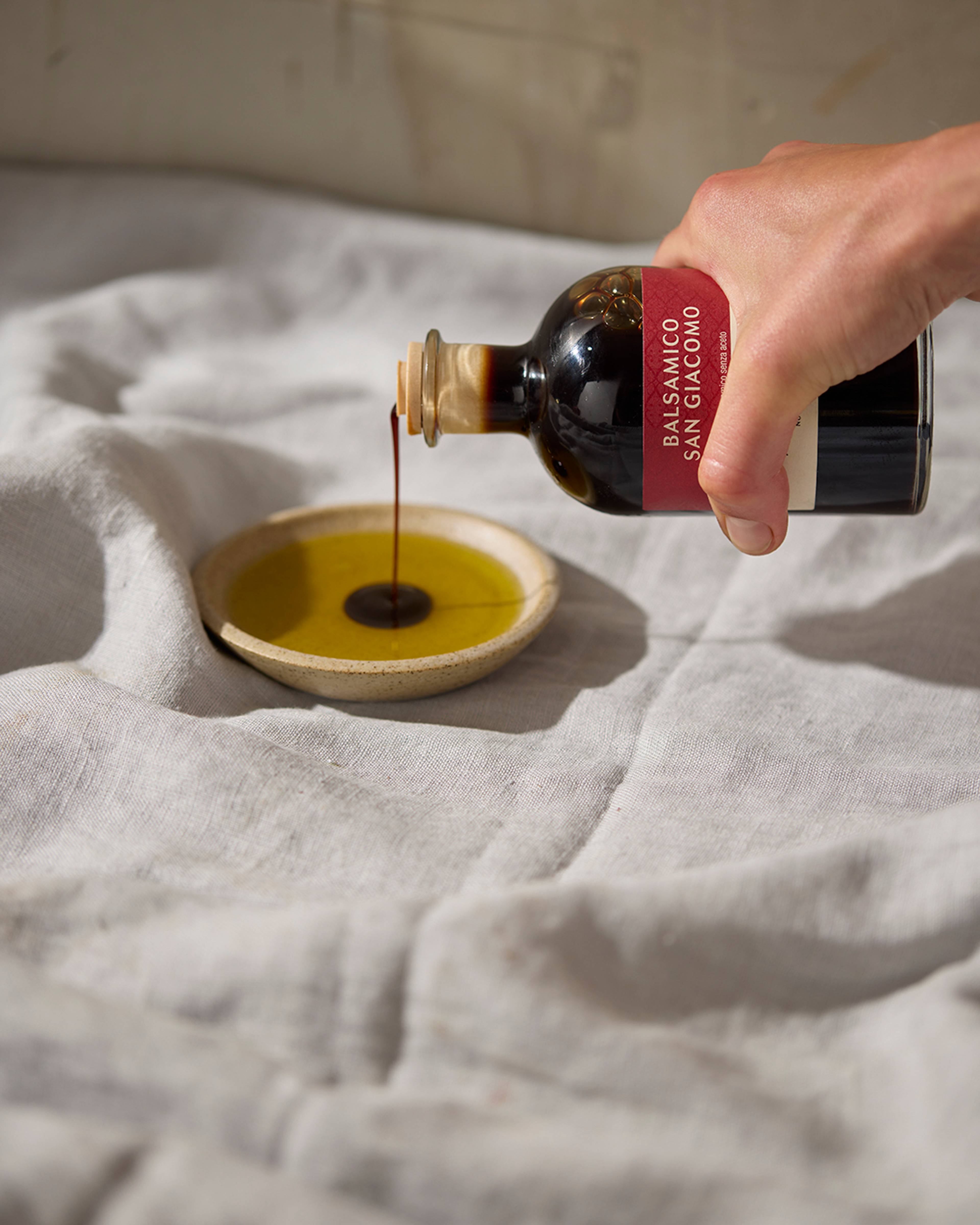 balsamic vinegar being poured onto a small plate of olive oil