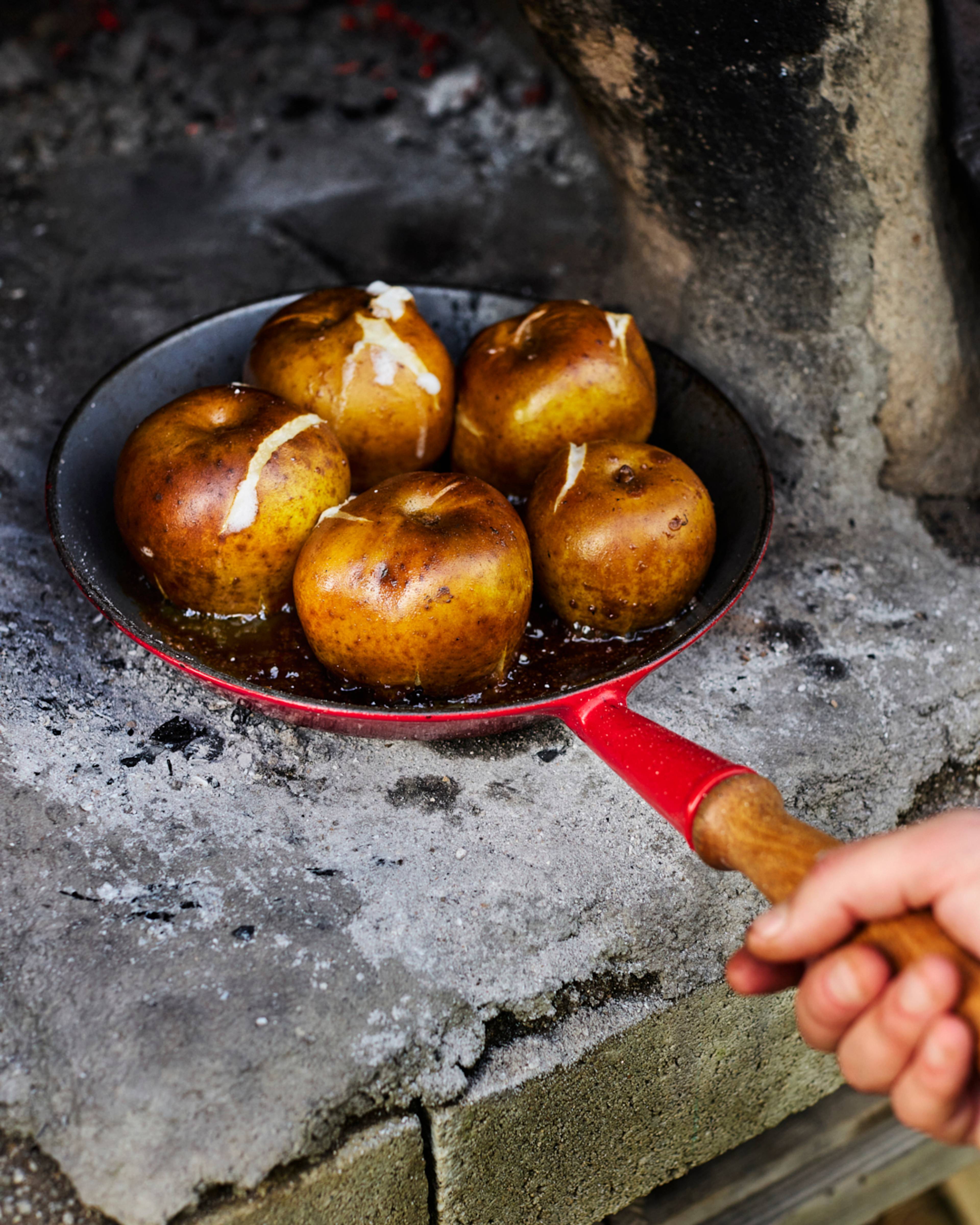 whole apples going in to roast in the fire