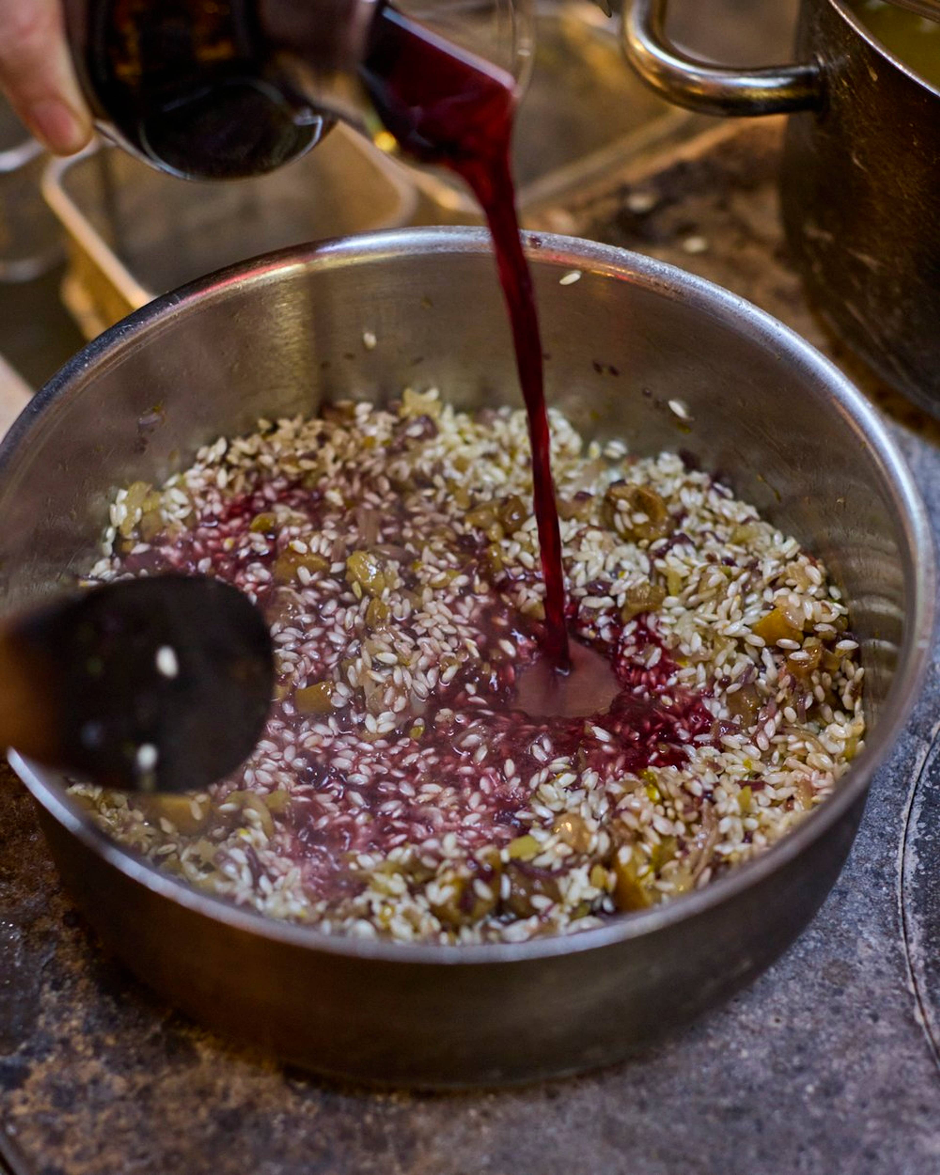red wine being poured in the risotto
