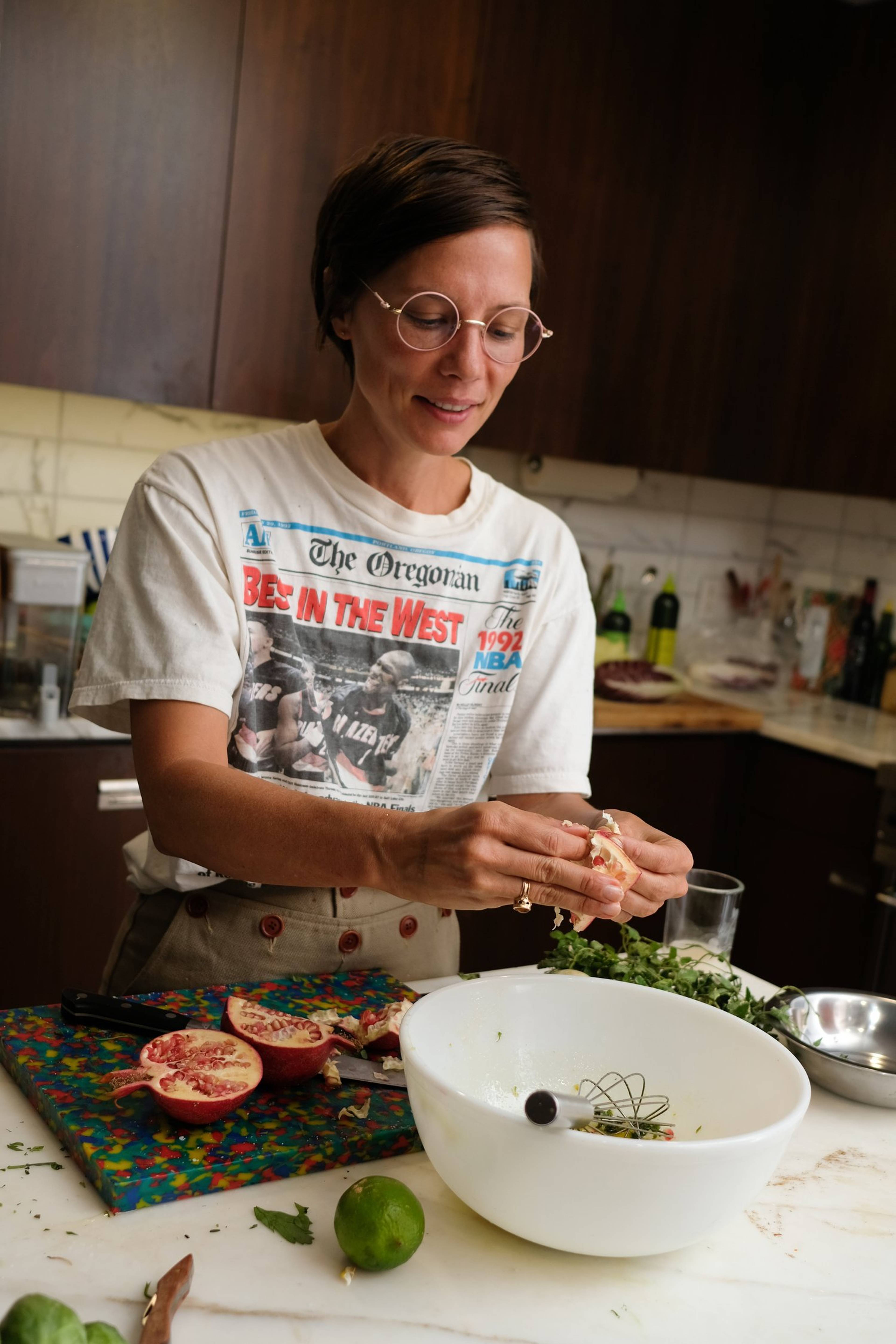 chris taking fresh pomegranate seeds out of the fruit into a bowl