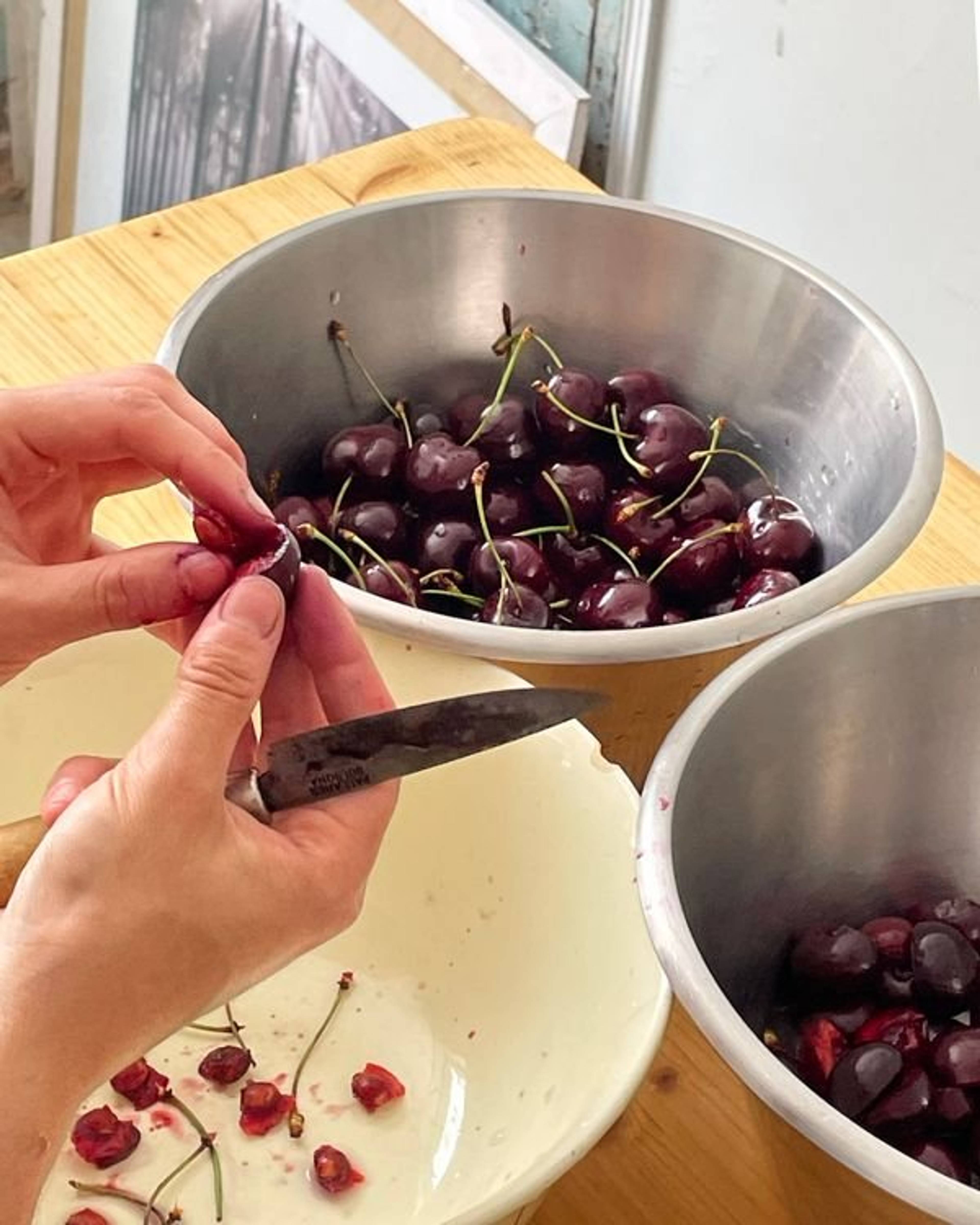 slicing cherries in half and transferring to a silver bowl