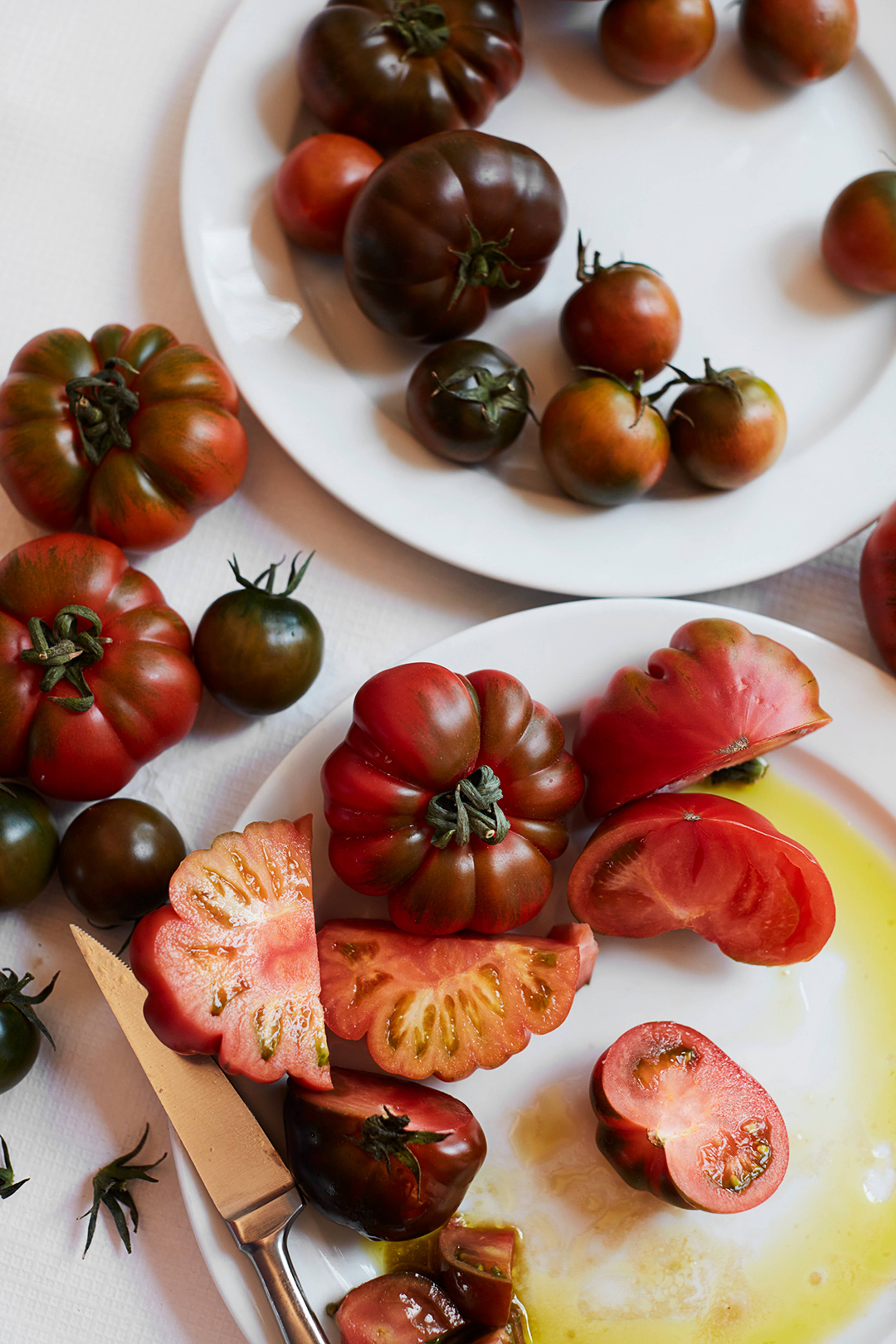 tomatoes of different shapes and sizes cut open on a plate