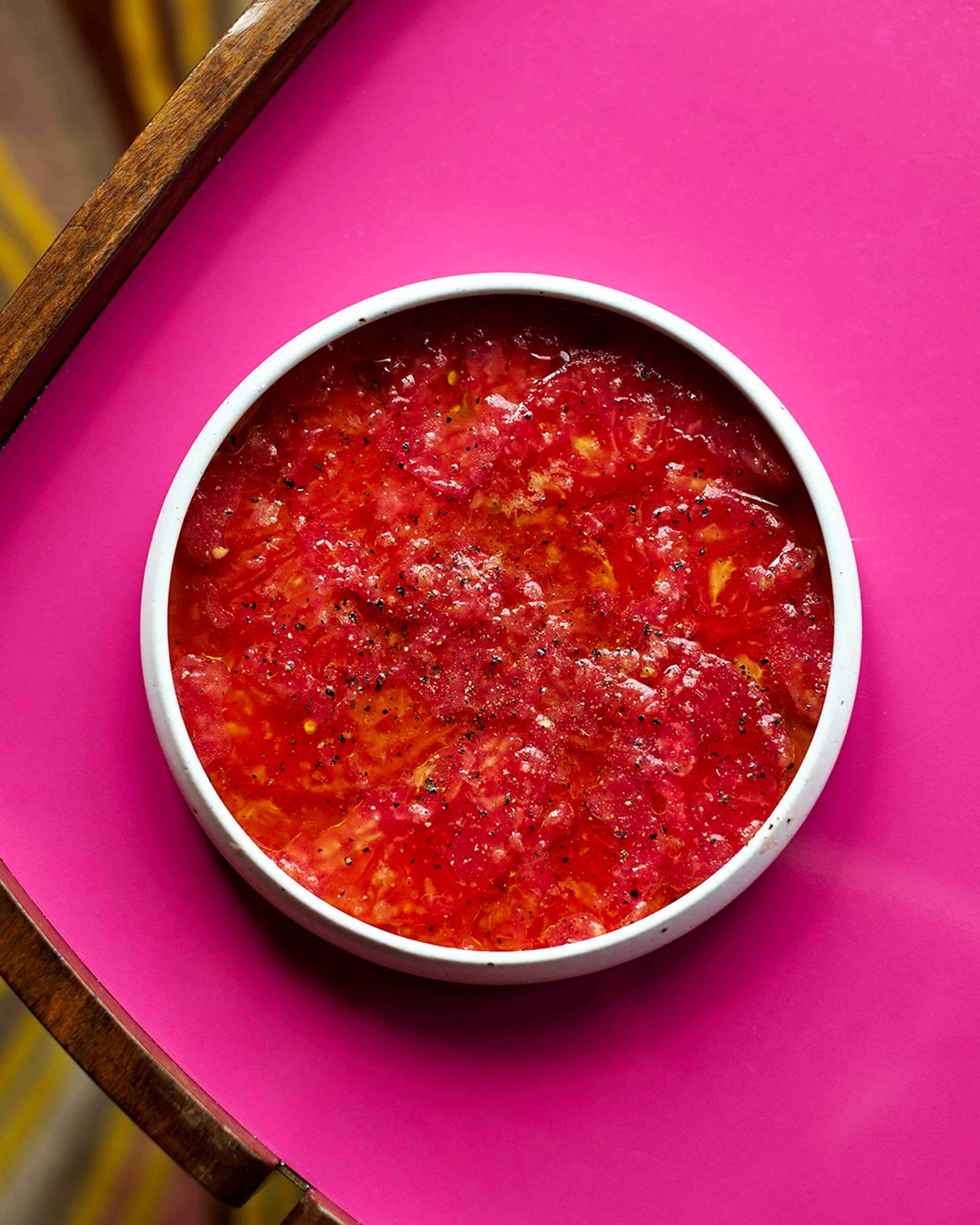 tomato salad served in a bowl on a pink background