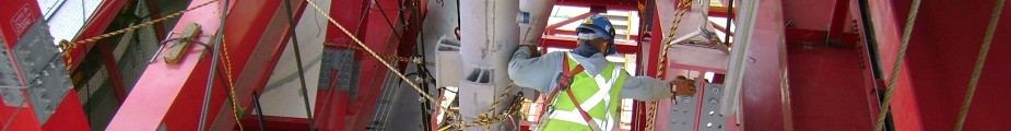 Trabajador con casco y chaleco reflectivo junto a una estructura industrial