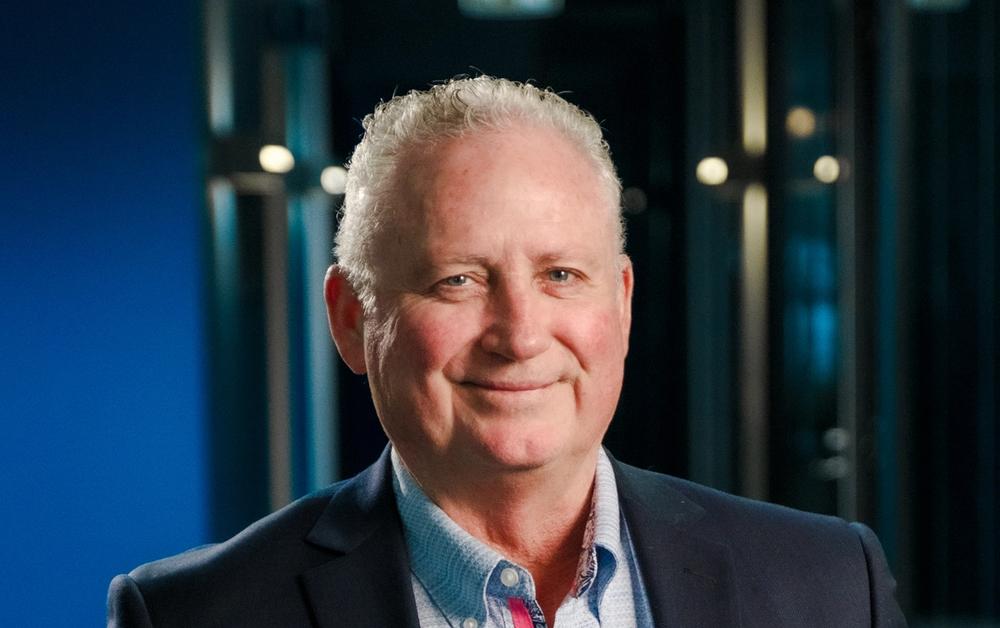 a man in a suit and blue shirt smiles for the camera