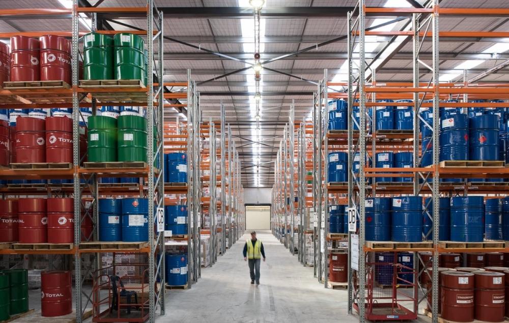 a man is carrying a stack of cans in a factory . a man is carrying a stack of cans in a factory .