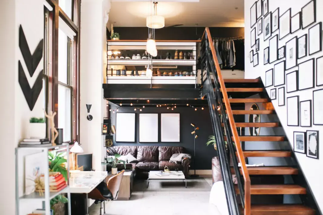 Loft studio with a mezzanine storage level, wooden staircase and gallery wall
