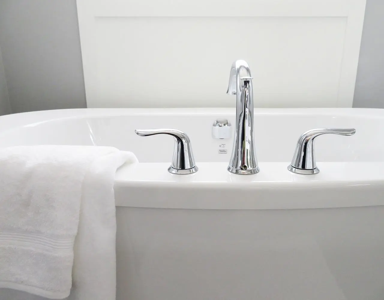 White freestanding bathtub with a chrome faucet and a folded white towel