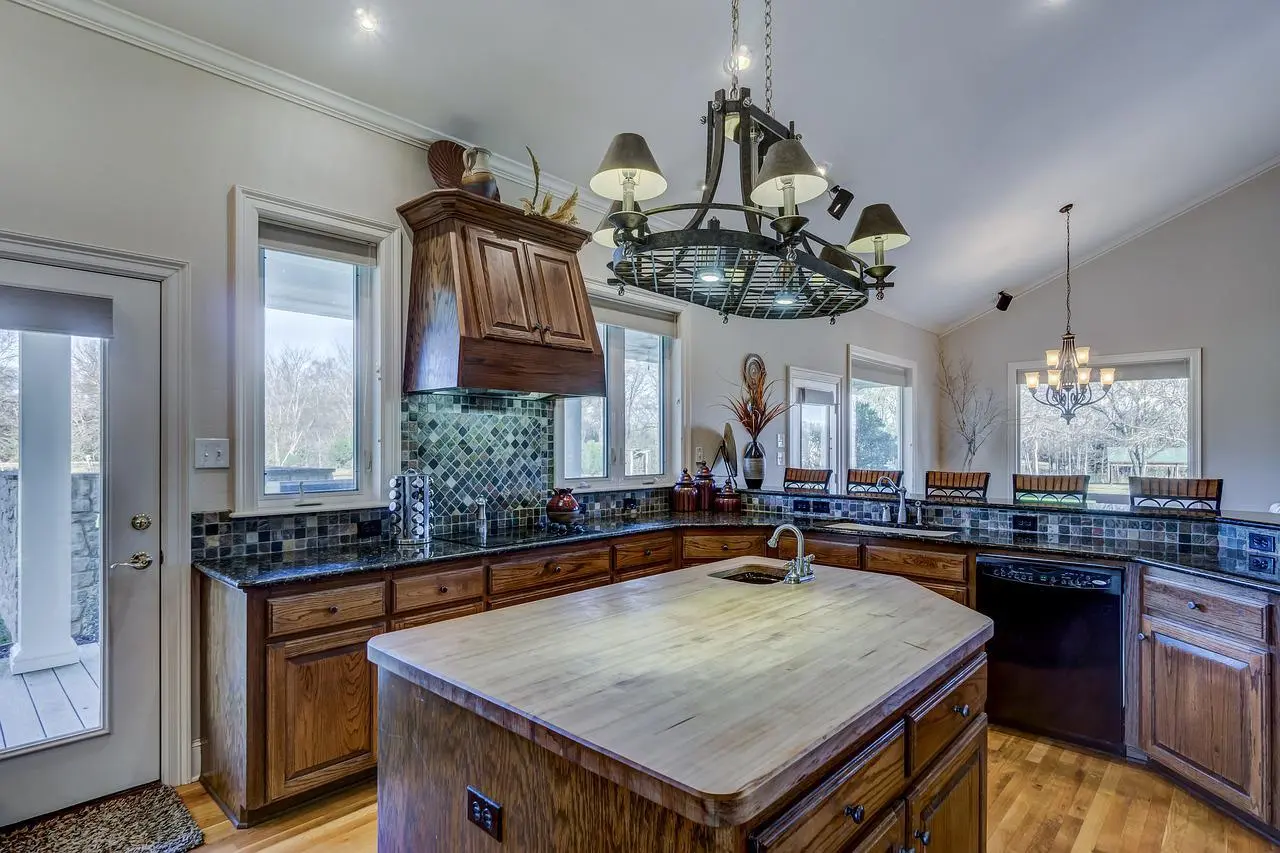 Wooden kitchen with a butcher block island and a wrought iron chandelier