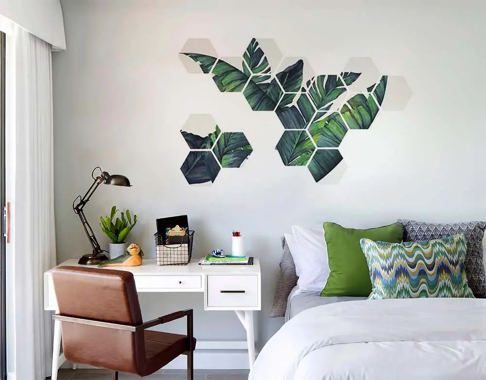 Bedroom desk under hexagon wall tiles painted with tropical leaves