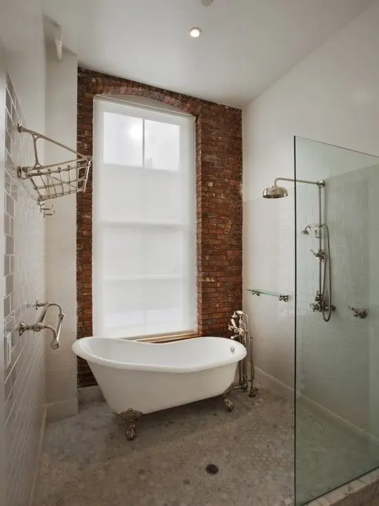 Clawfoot bathtub beside a separate glass walk-in shower and a brick wall