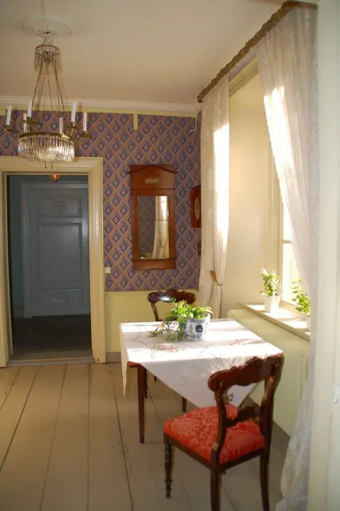 Old-fashioned room with patterned wallpaper, a chandelier and a lace-covered table