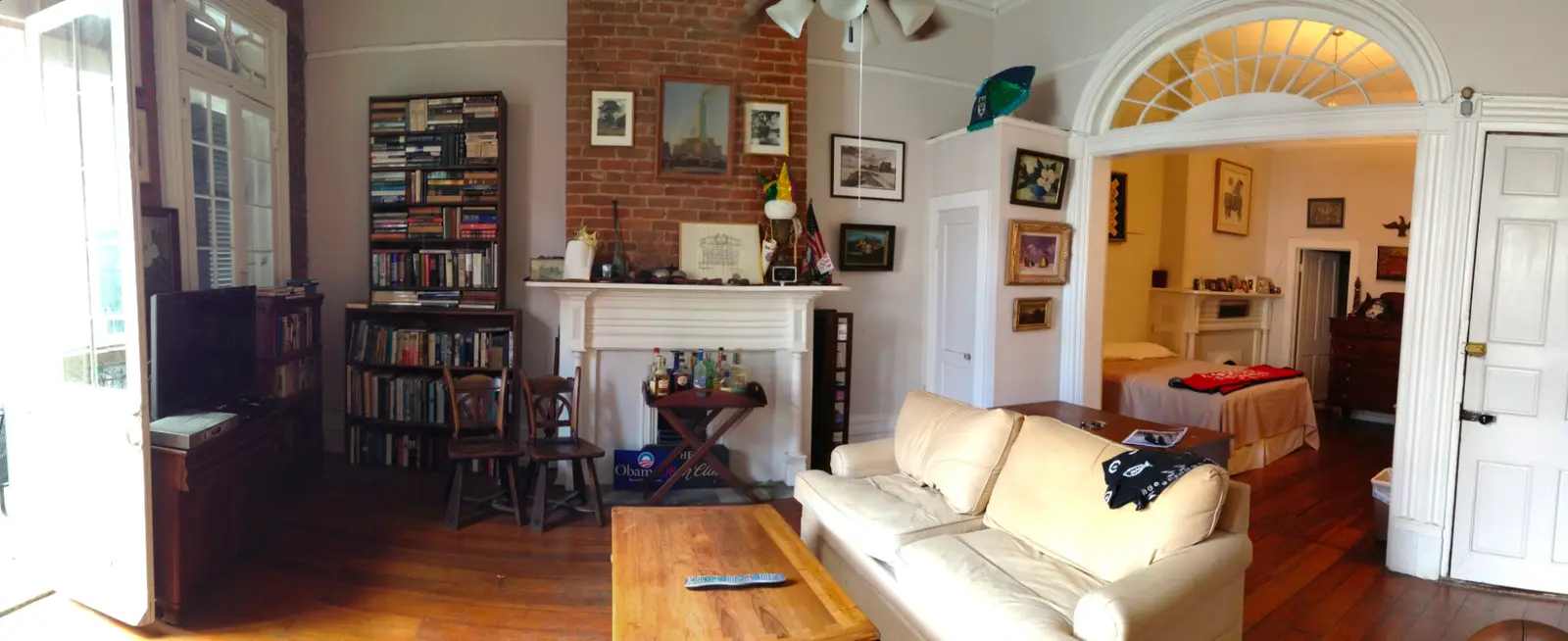 Panorama of an old apartment with a fanlight arch, a fireplace, bookshelves and a cream sofa