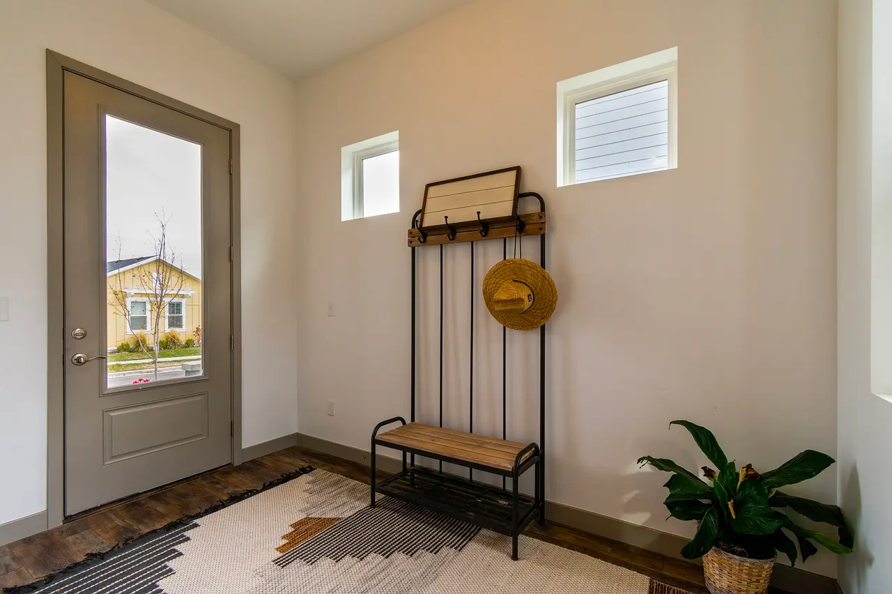 Entryway with a metal coat rack bench, a patterned rug, a plant and a glass front door