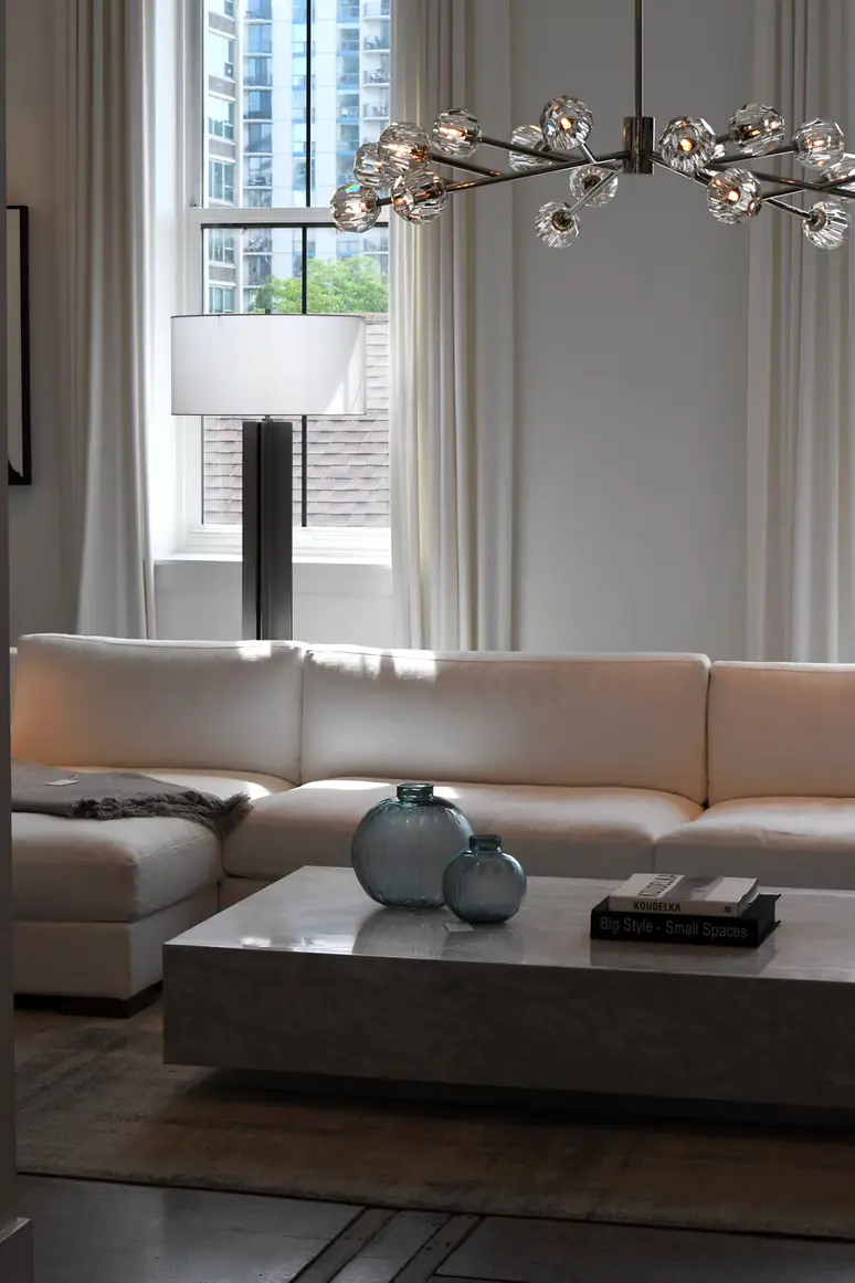 Living room with a branch-style glass chandelier above a cream sofa and stone coffee table