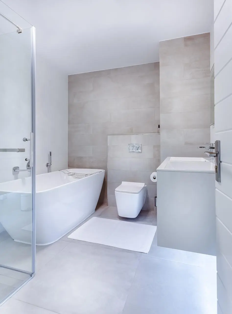 Minimalist bathroom with light grey large-format tiles, a freestanding tub and wall-hung toilet