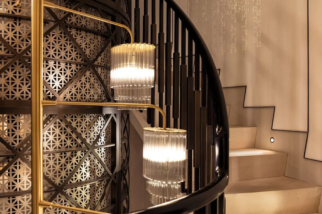 Spiral staircase with geometric lattice panels and glass pendant lights