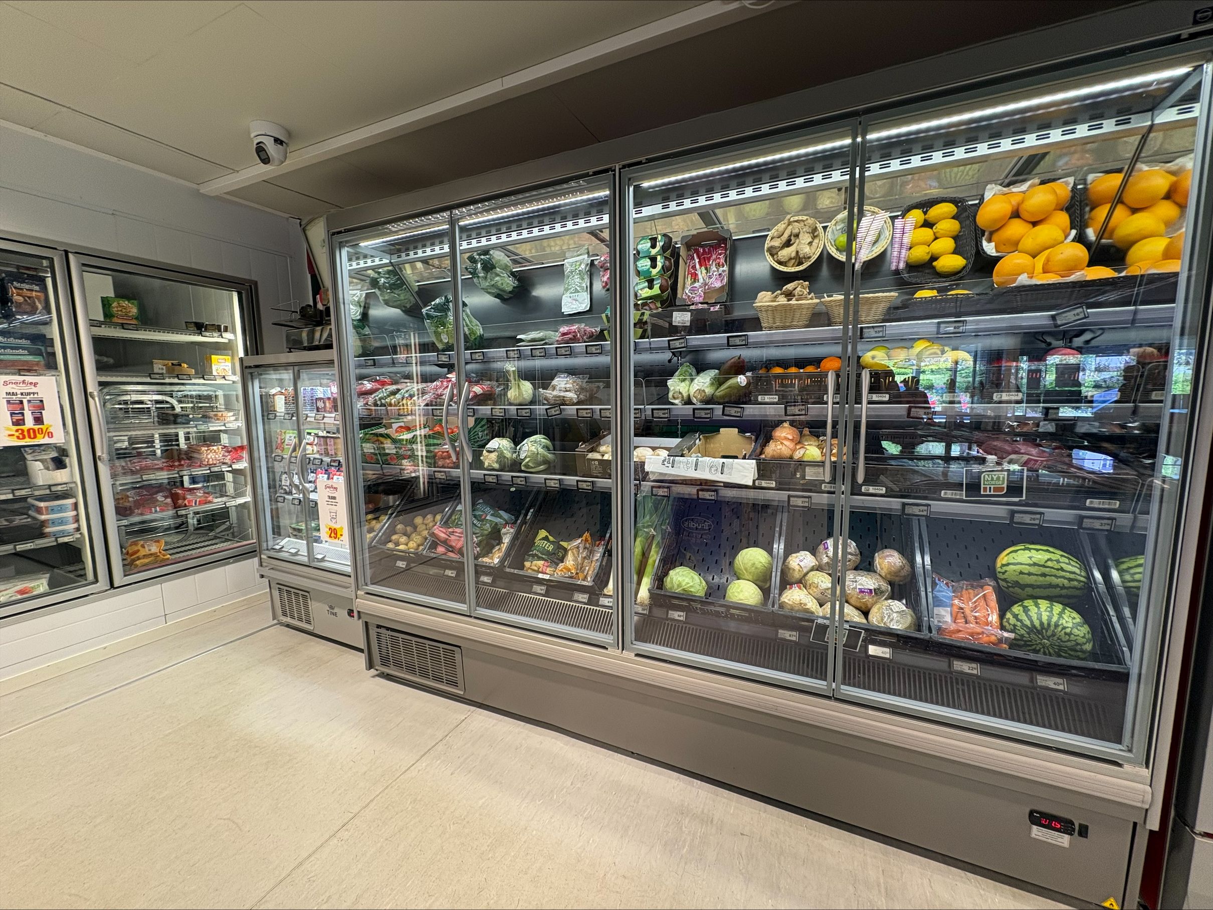 A refrigerated display case in a store filled with fresh fruits and vegetables.