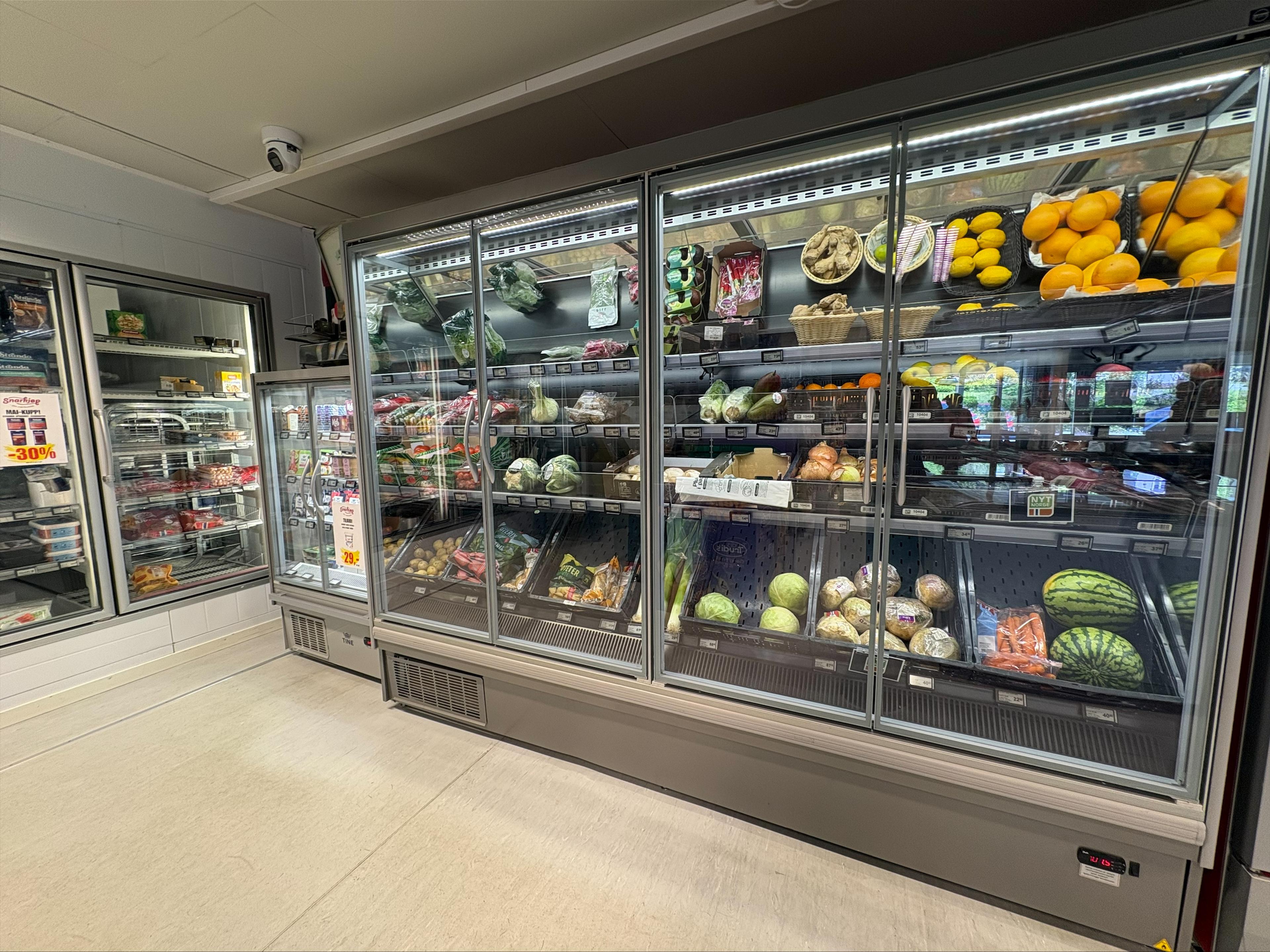 A refrigerated display case in a store filled with fresh fruits and vegetables.