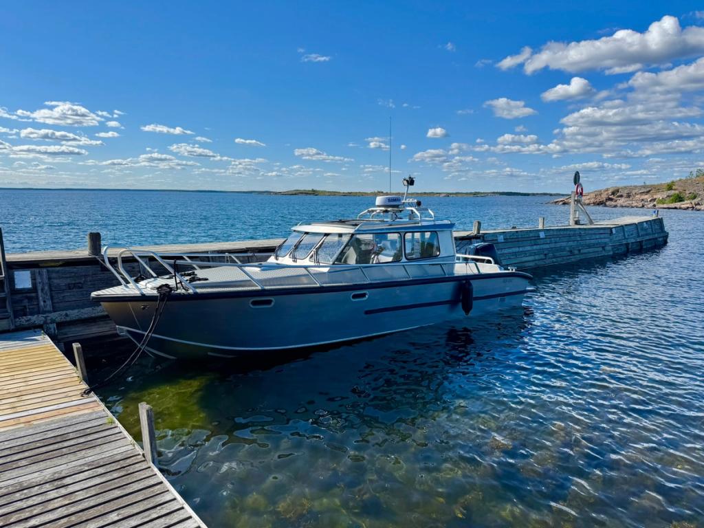 Flanör vid en väderbiten träbrygga i ytterskärgården under blå himmel.