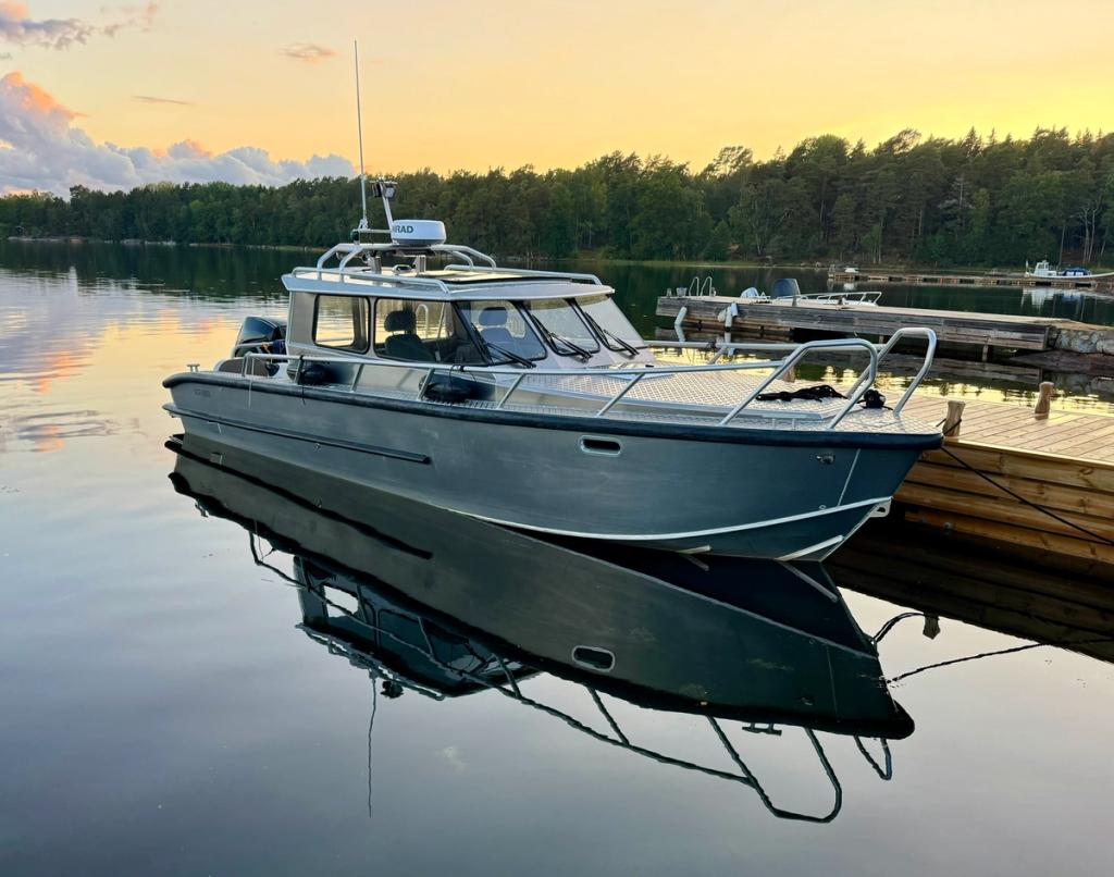 Flanör förtöjd vid bryggan i kvällsljus, speglad i stilla vatten.