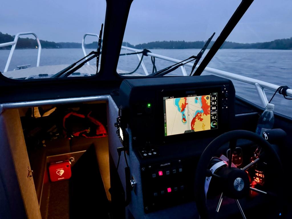 Flanörs upplysta förarplats under mörkerkörning, med sjökortet på plottern.