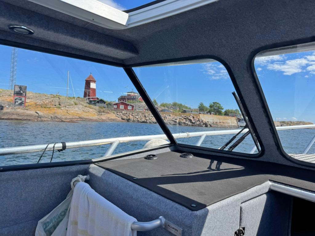 Utsikt från Flanörs hytt mot ett rött båk och skärgårdshus på en klippö.