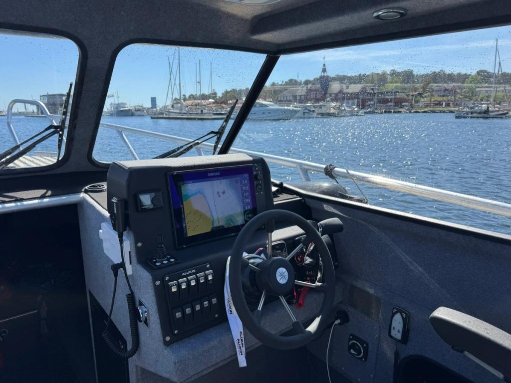 Flanörs förarplats med sjökortsplotter och ratt på väg in mot en gästhamn.