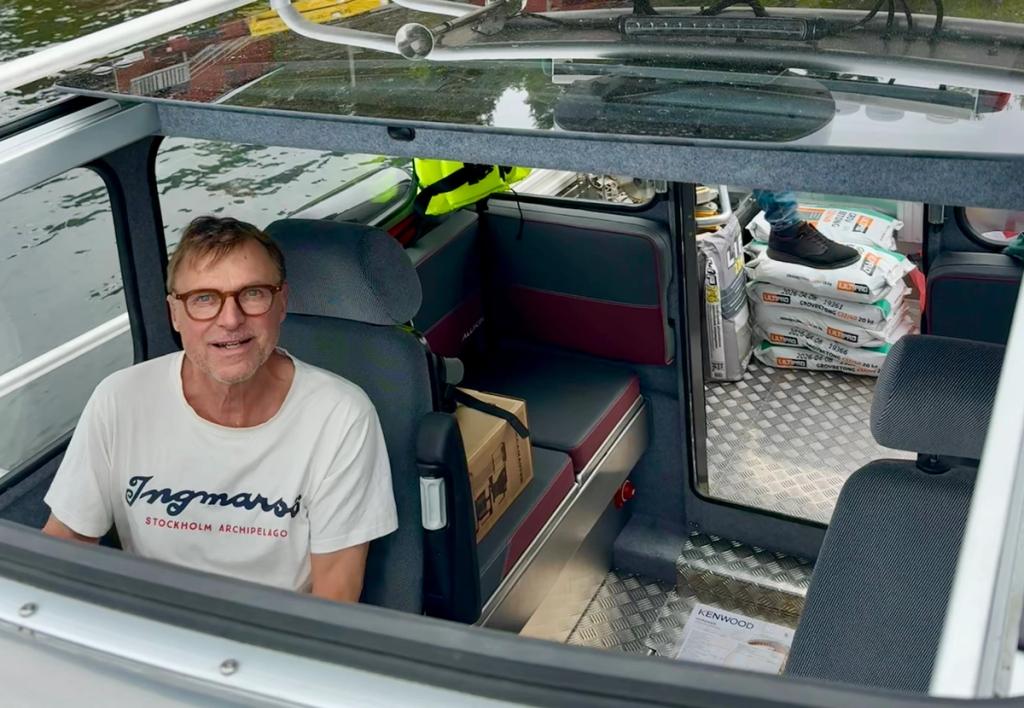 Niklas Forsén vid rodret med cementsäckar, kartonger och vitvaror lastade bakom sig.