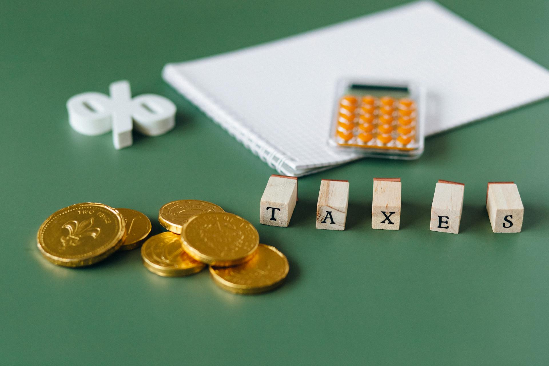 Gold Coins on Green Surface with the word "TAXES"